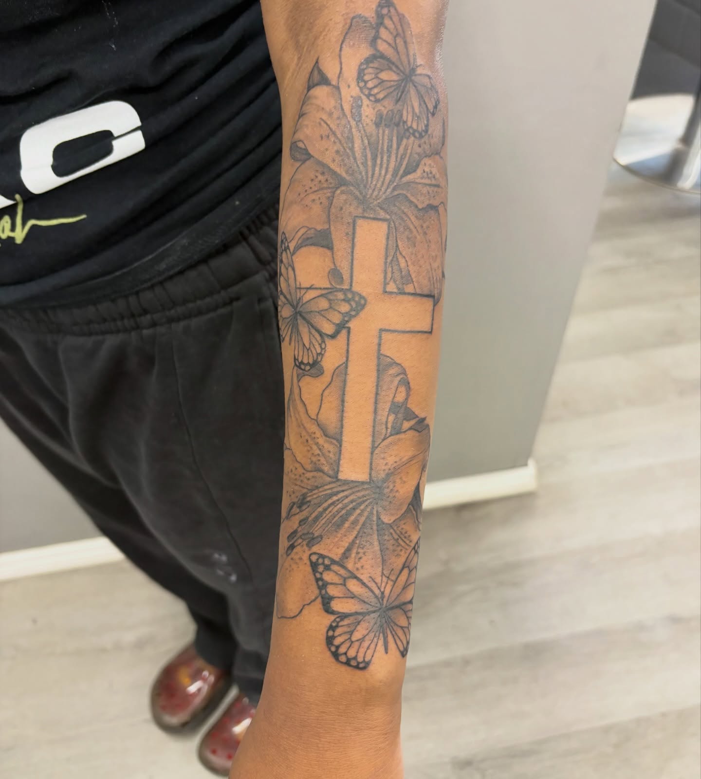 Cross with butterflies and flowers realism tattoo on the forearm by Detroit Tattoo Artist
