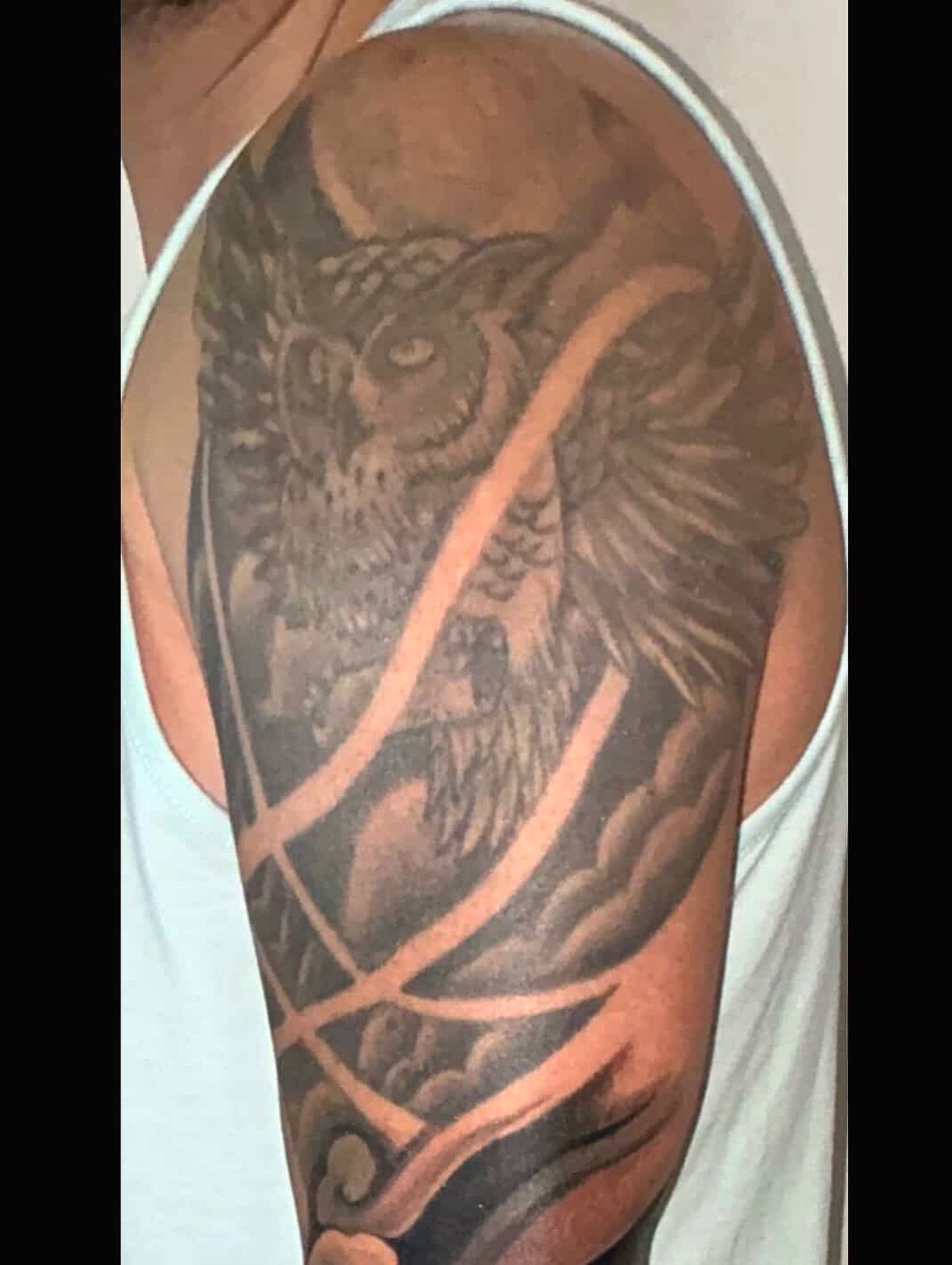 Owl black and grey tattoo on the upper arm by Luis Gil