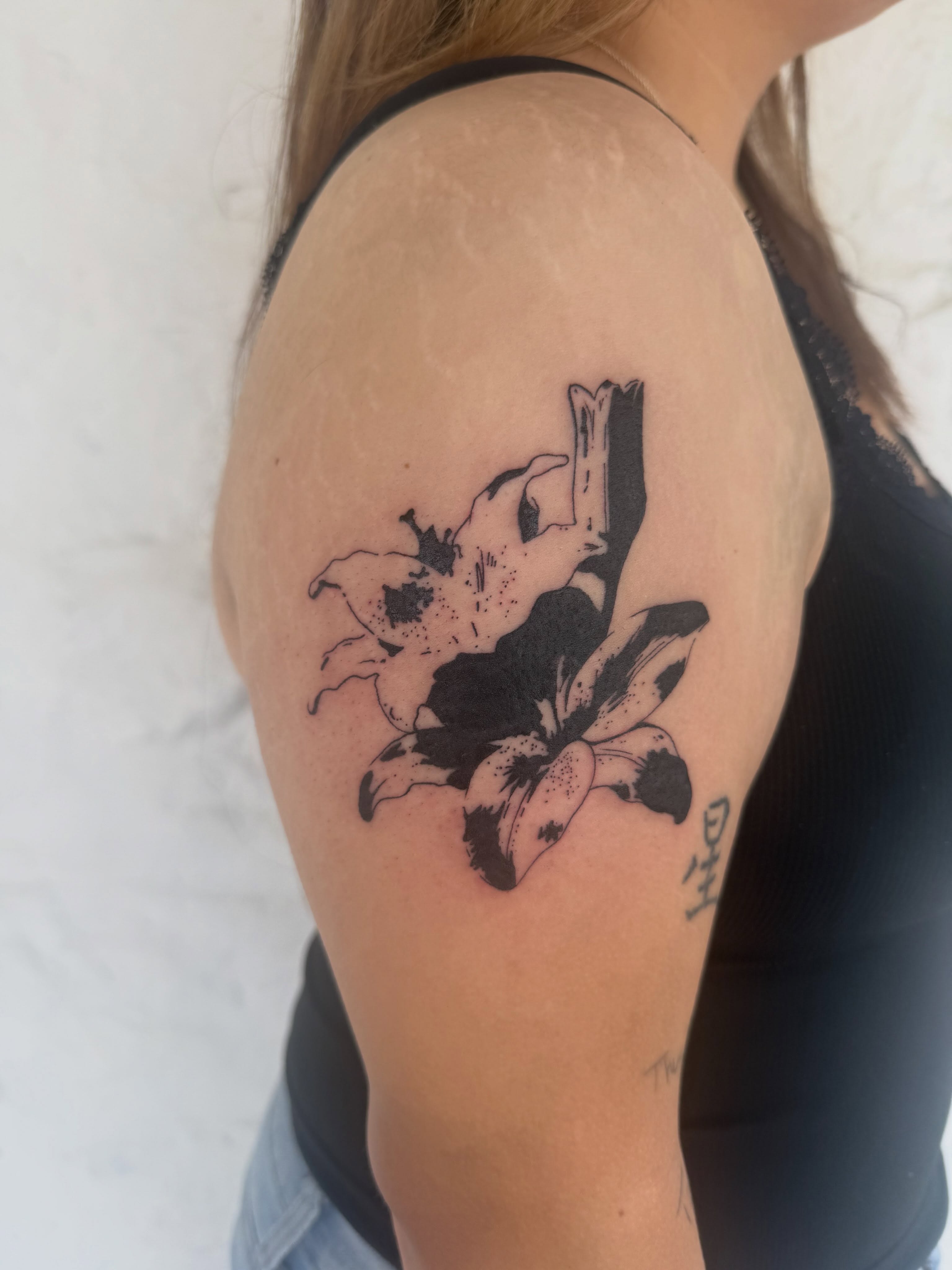 Lily black and grey tattoo on the shoulder by sarah