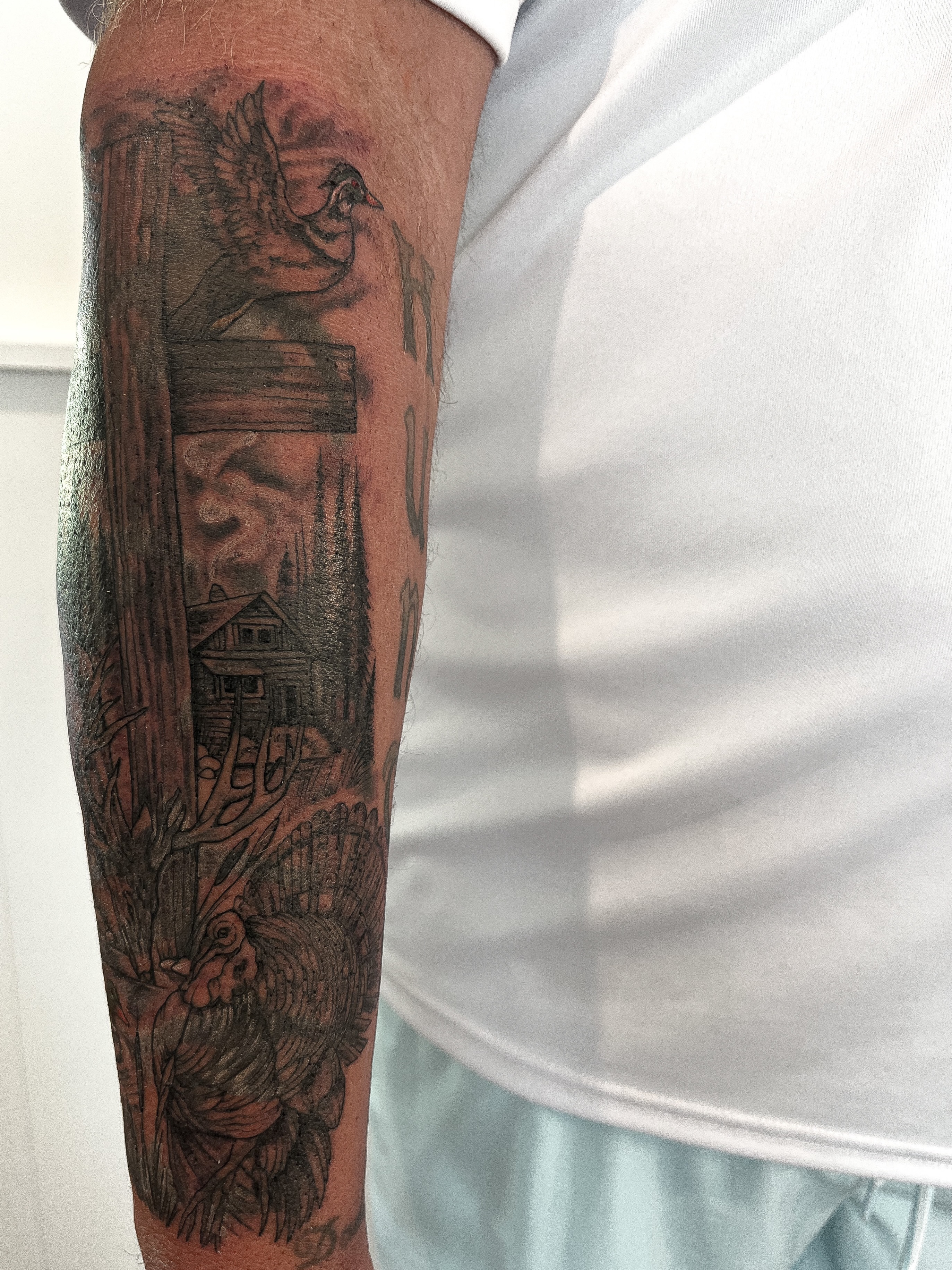 Bird and house black and grey tattoo on the forearm by Janelle Cuba