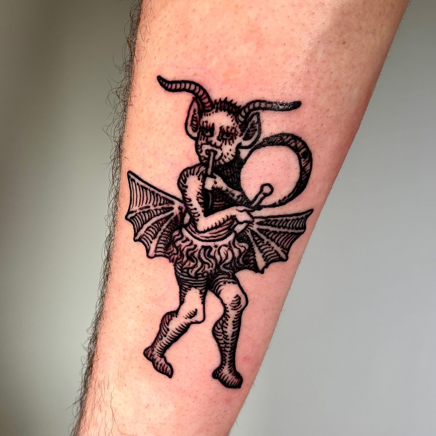 Demons playing instruments black and grey tattoo on the forearm by ๐๐๐ ๐๐๐๐๐๐๐๐๐๐๐