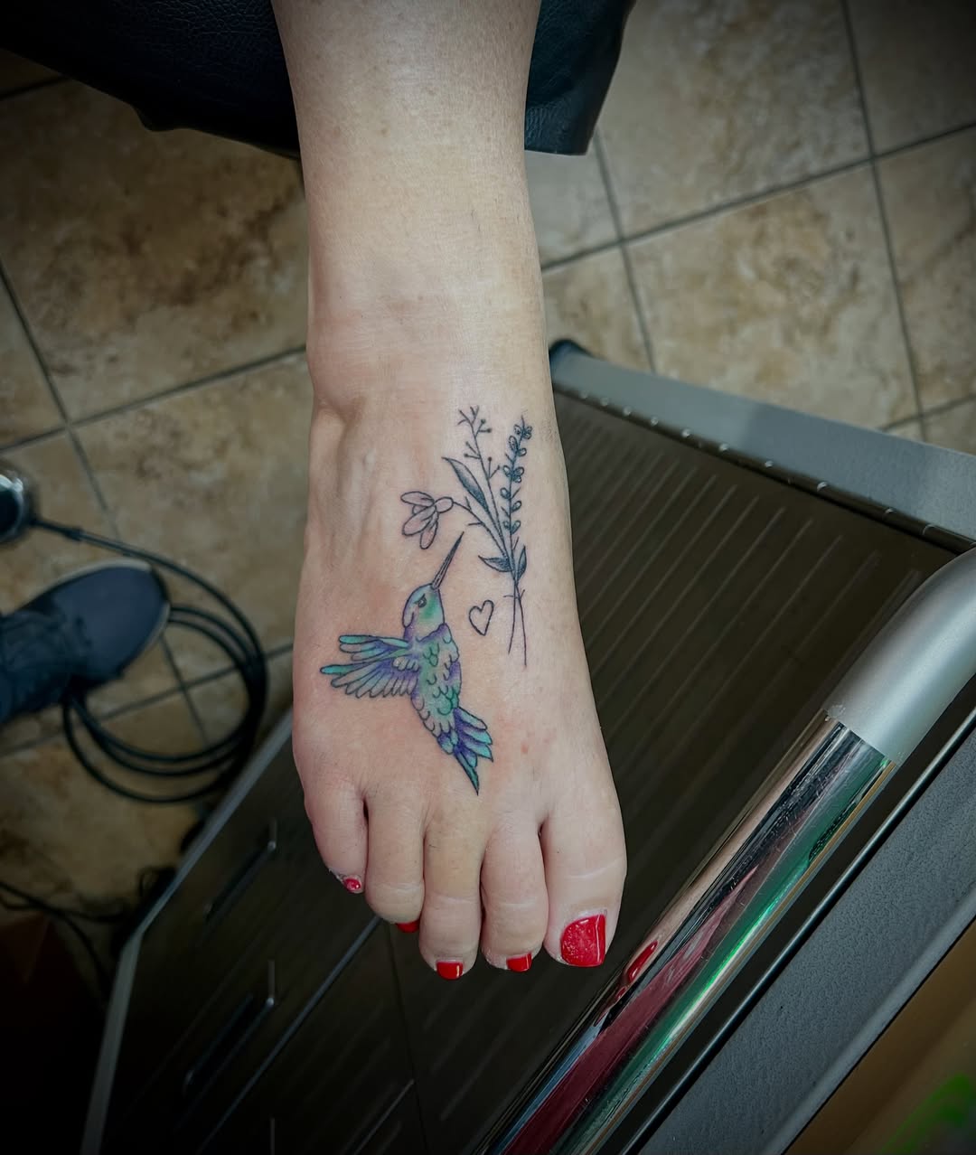 Hummingbird and flower new school tattoo on the foot by Austin Hill