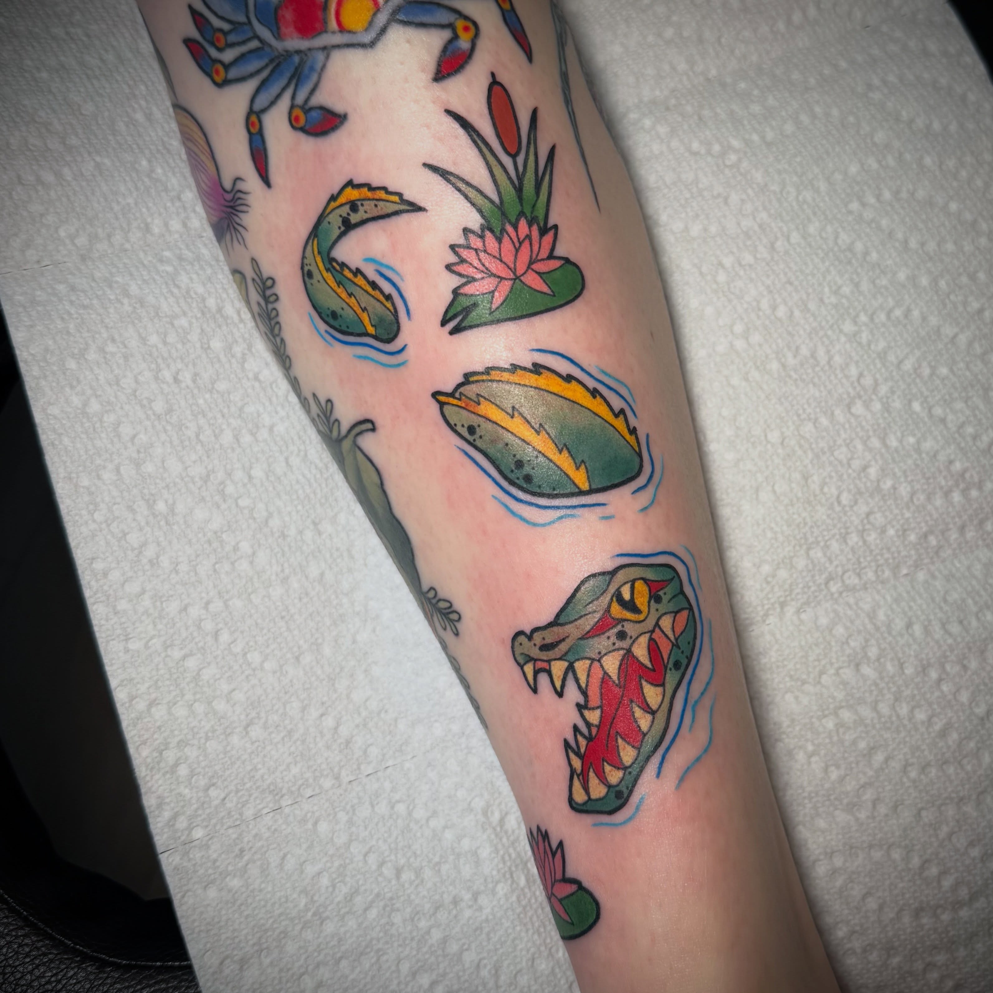 Crocodile and lily pads American traditional tattoo on the forearm by Lyndze Masters