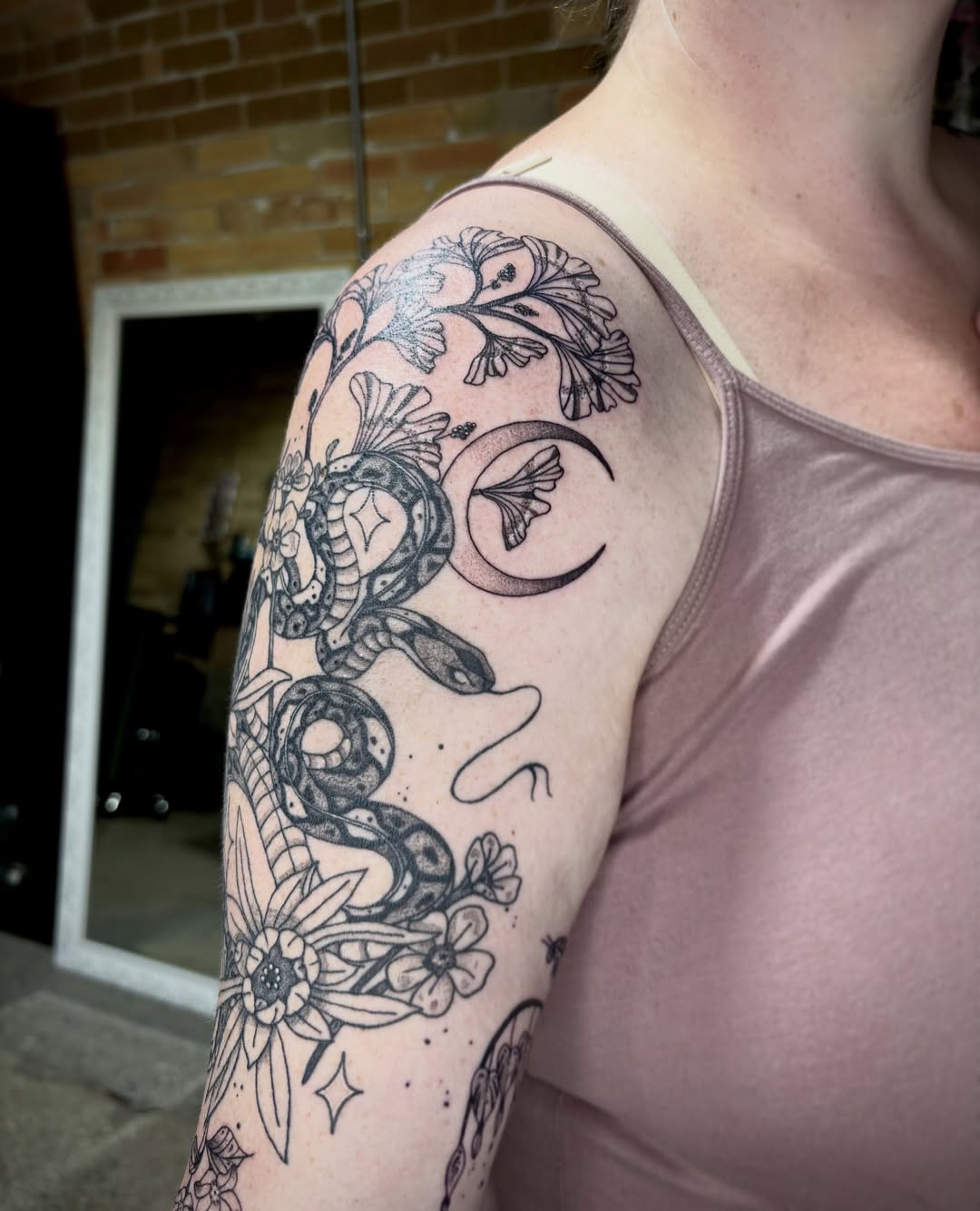 Snake and flowers dotwork tattoo on the upper arm by destiney rose