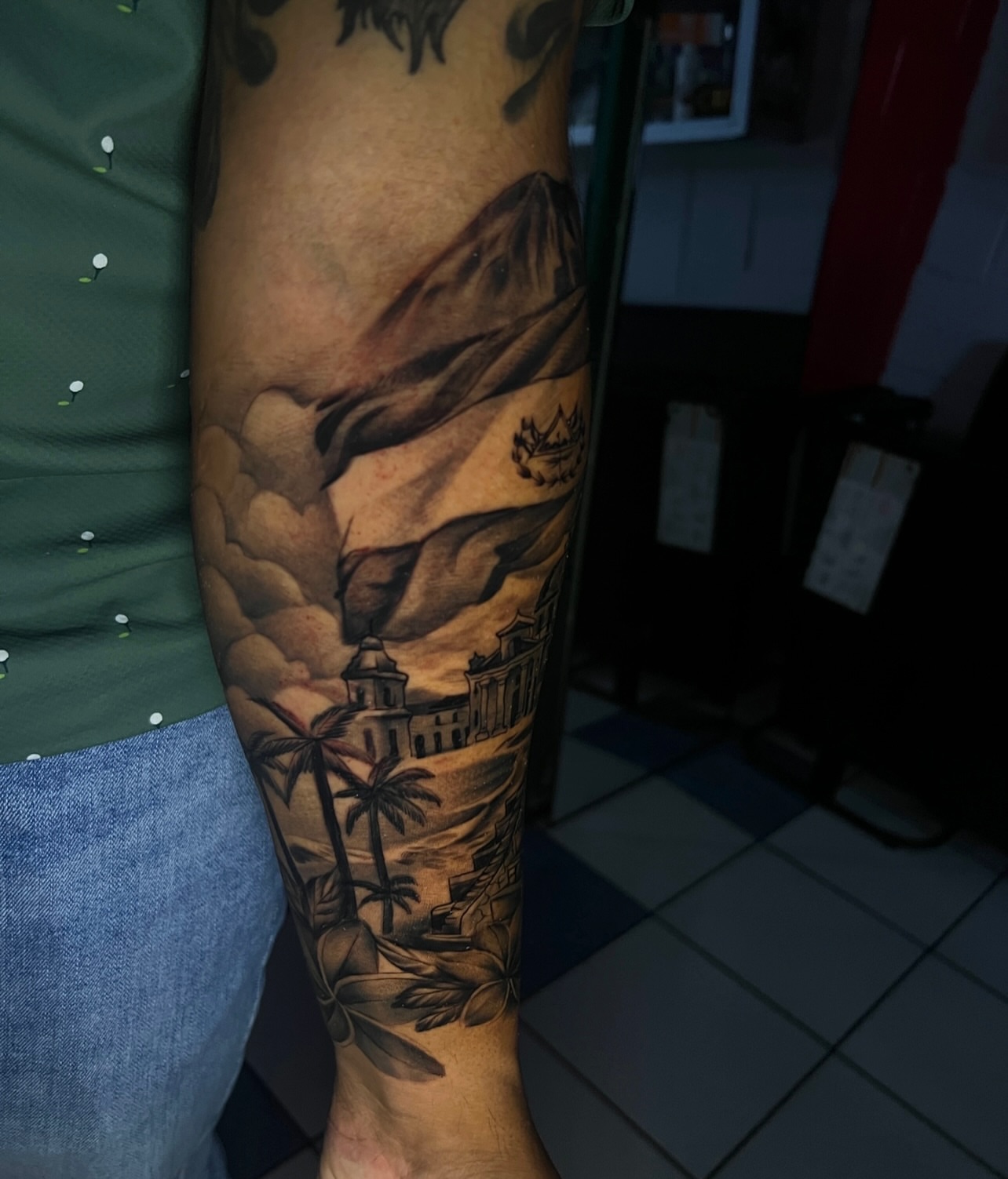 Landscape with buildings and palm trees realism tattoo on the forearm by El Salvador Tattoo Artist