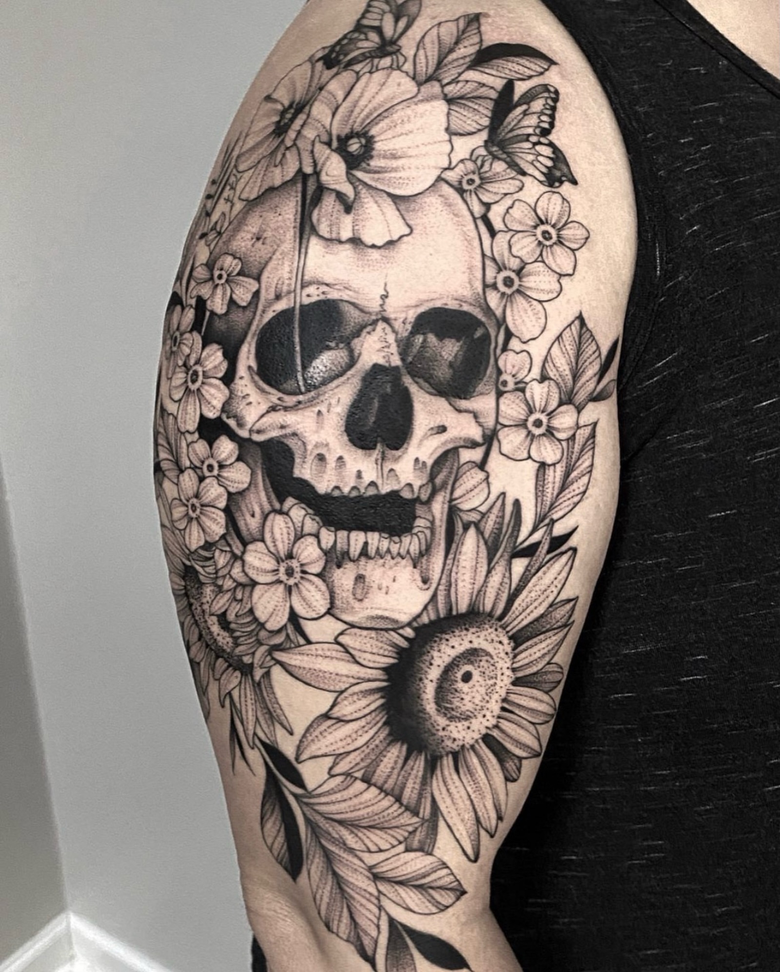 Skull and flowers realism tattoo on the upper arm by Sterling Grice