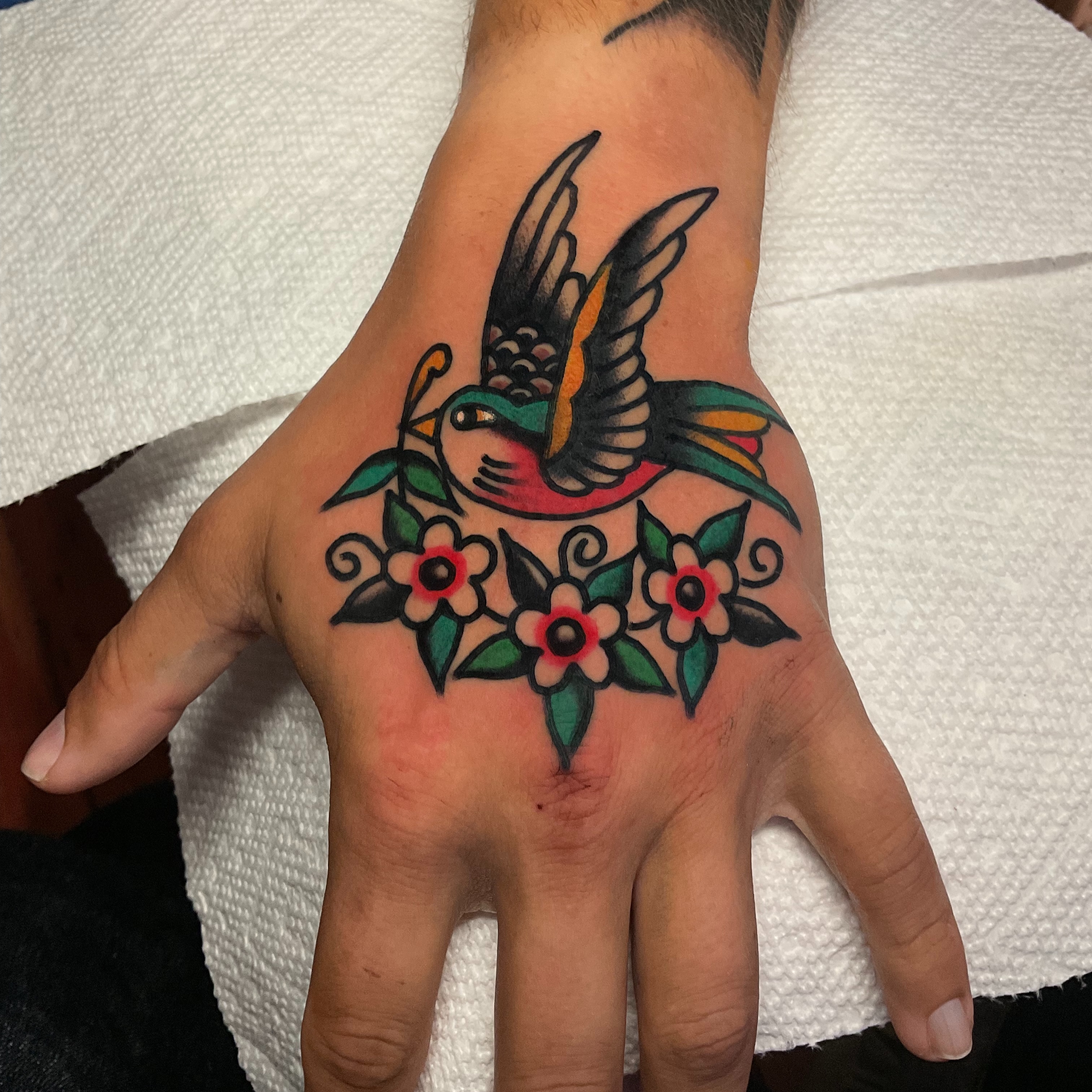Bird and flowers American traditional tattoo on the hand by Stevie Lowenstein, Cincinnati, Ohio