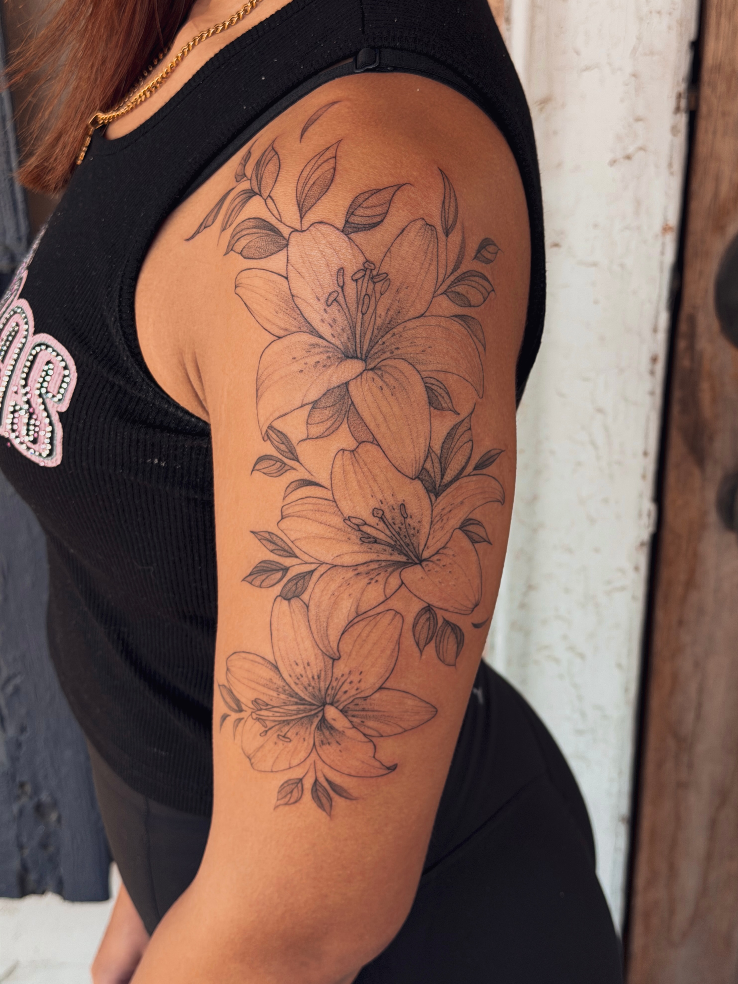 Lilies black and grey tattoo on the upper arm by Floral