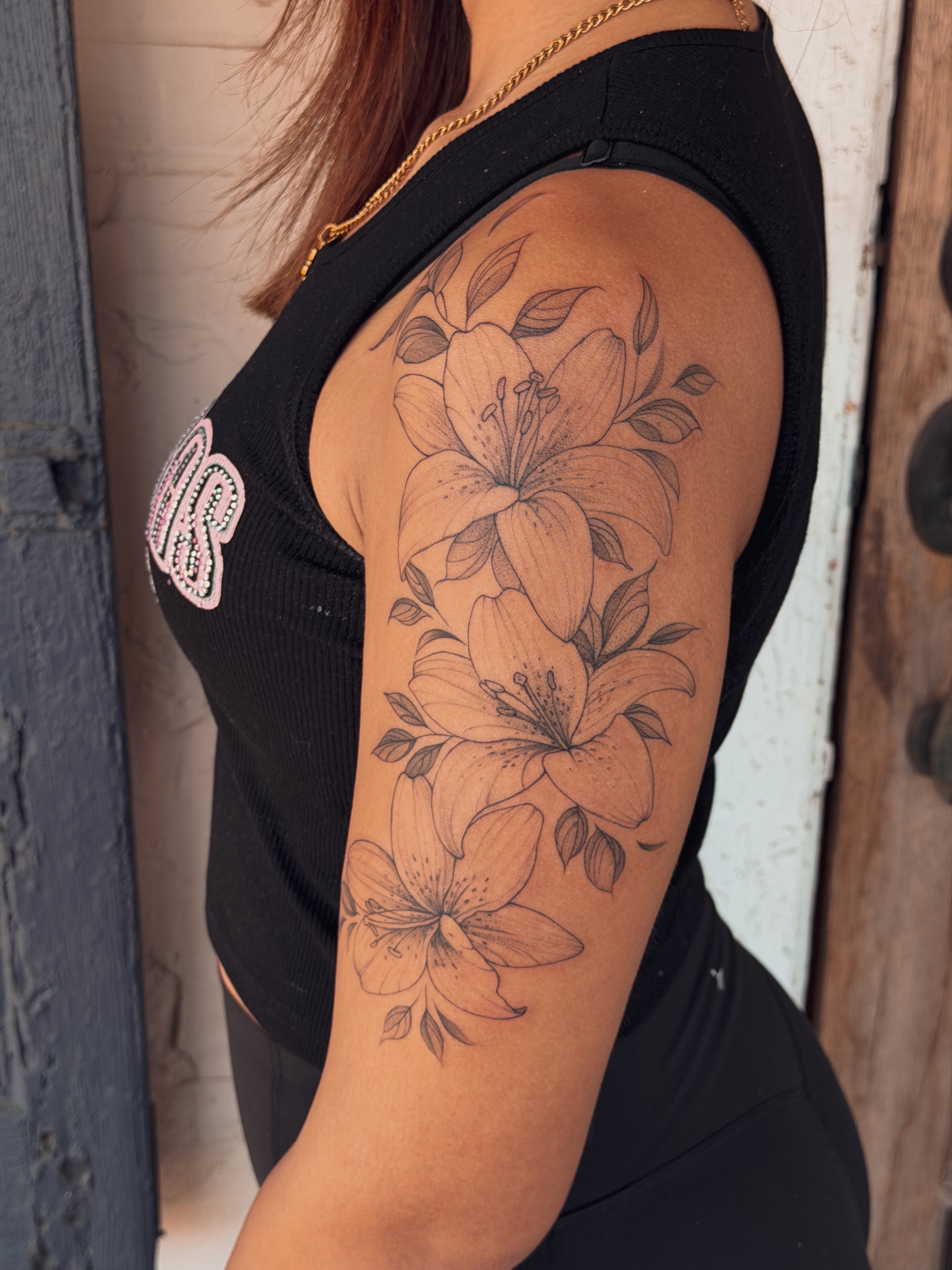 Lilies black and grey tattoo on the upper arm by Floral