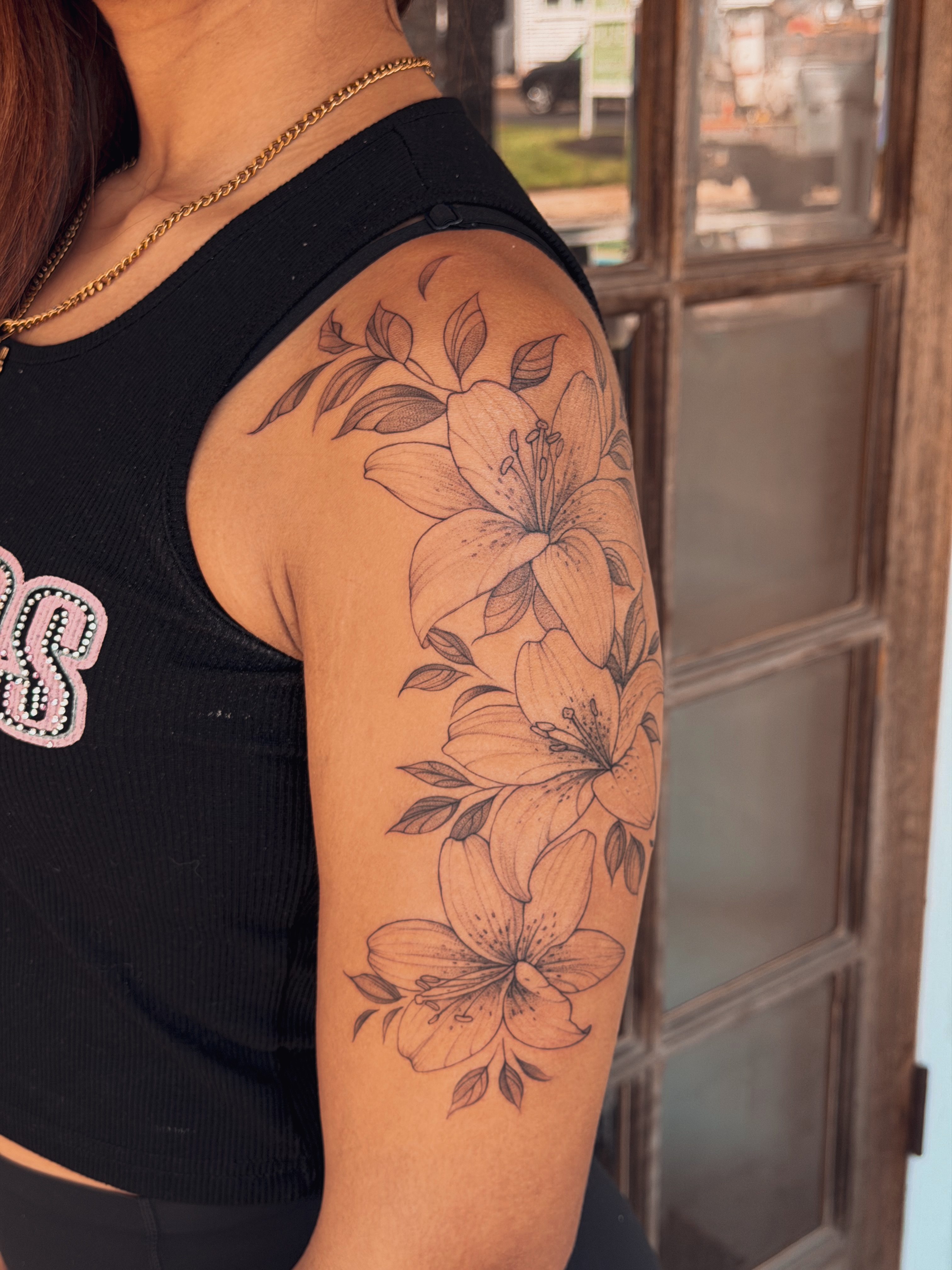 Lilies black and grey tattoo on the upper arm by Floral