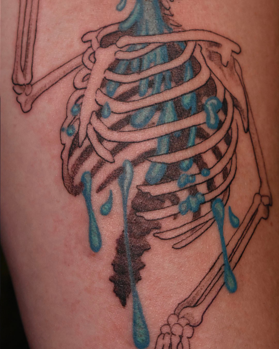 Ribs with dripping blue liquid black and grey tattoo on the thigh by Erin Isaacs
