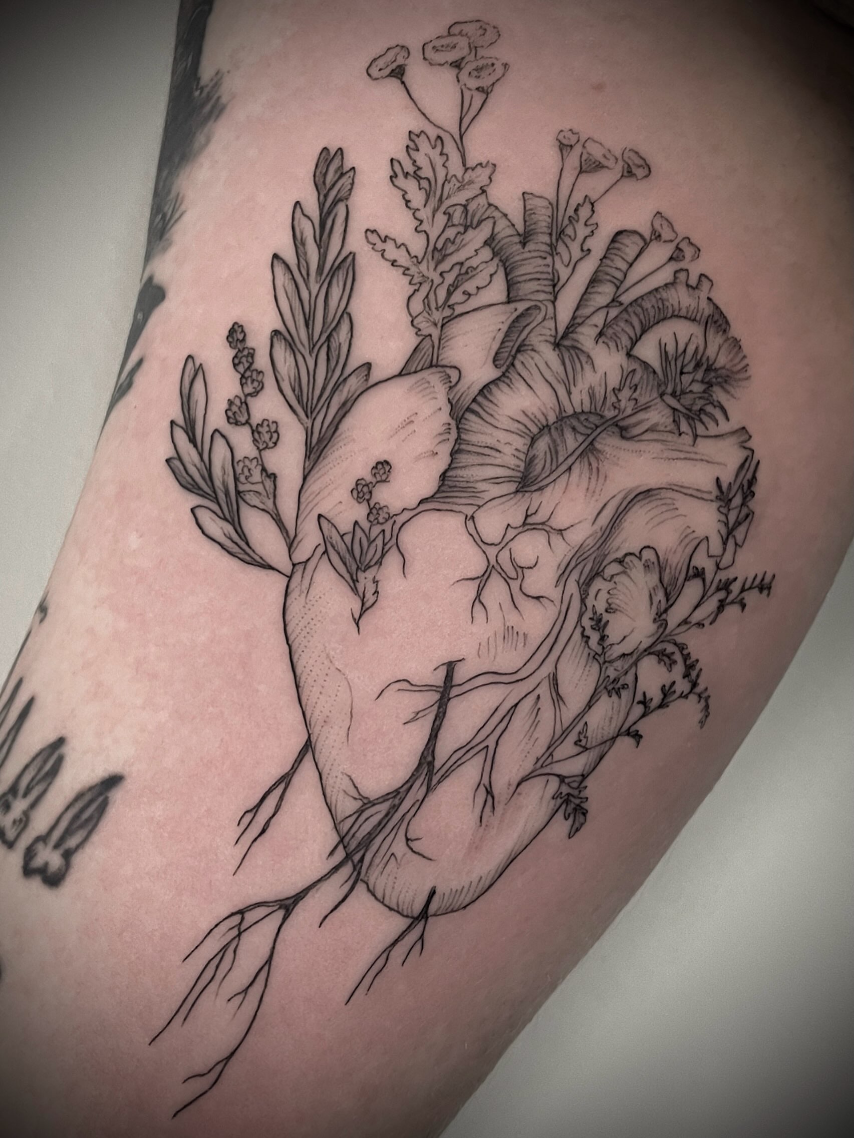 Heart with floral elements realism tattoo on the thigh by Christen Wolfe CA Tattooer
