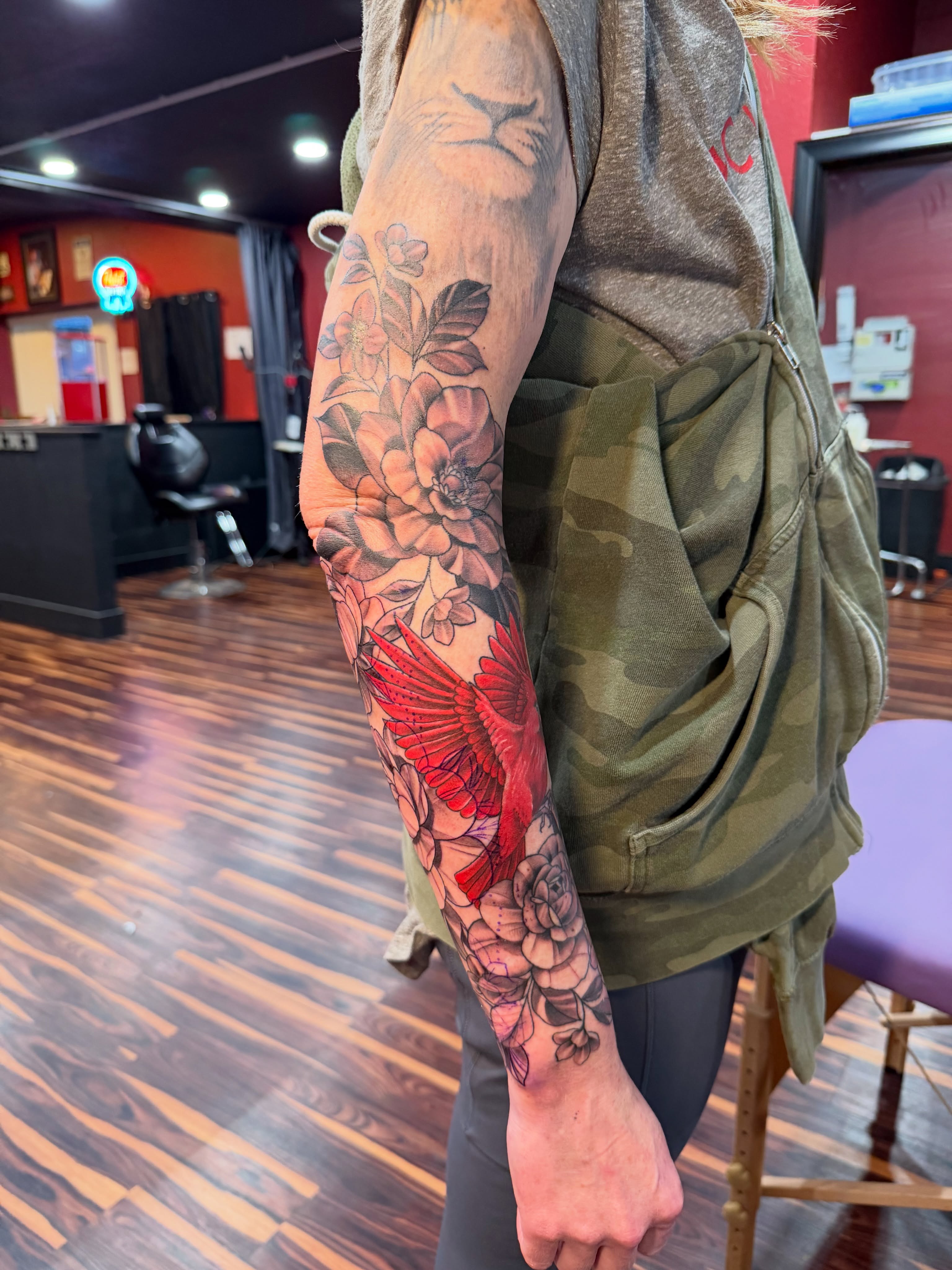 Red bird and floral bouquet realism tattoo on the forearm by TyAnne Schulte