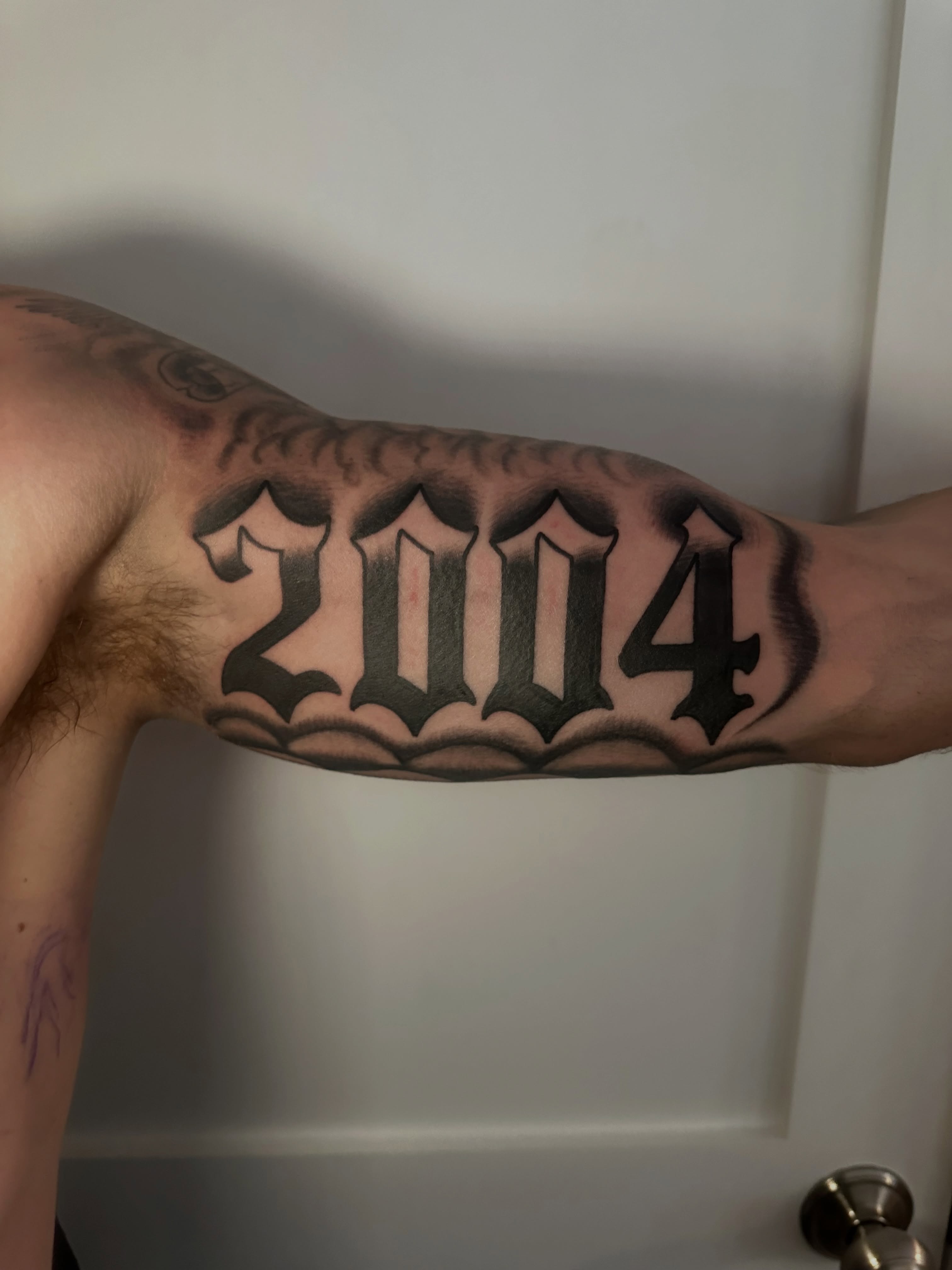 Year 2004 black and grey tattoo on the forearm by Drew’s Tattoos (NH)