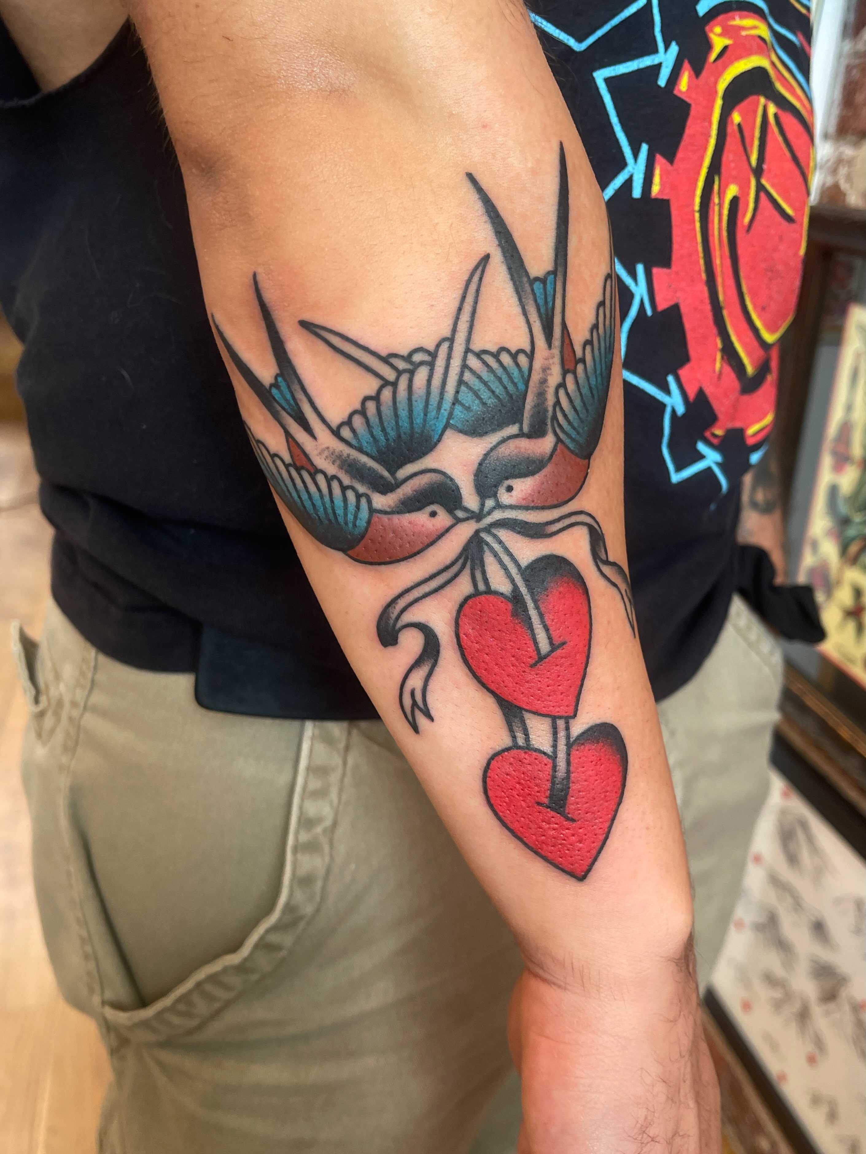 Swallows and hearts American traditional tattoo on the forearm by Spencer Reisbeck
