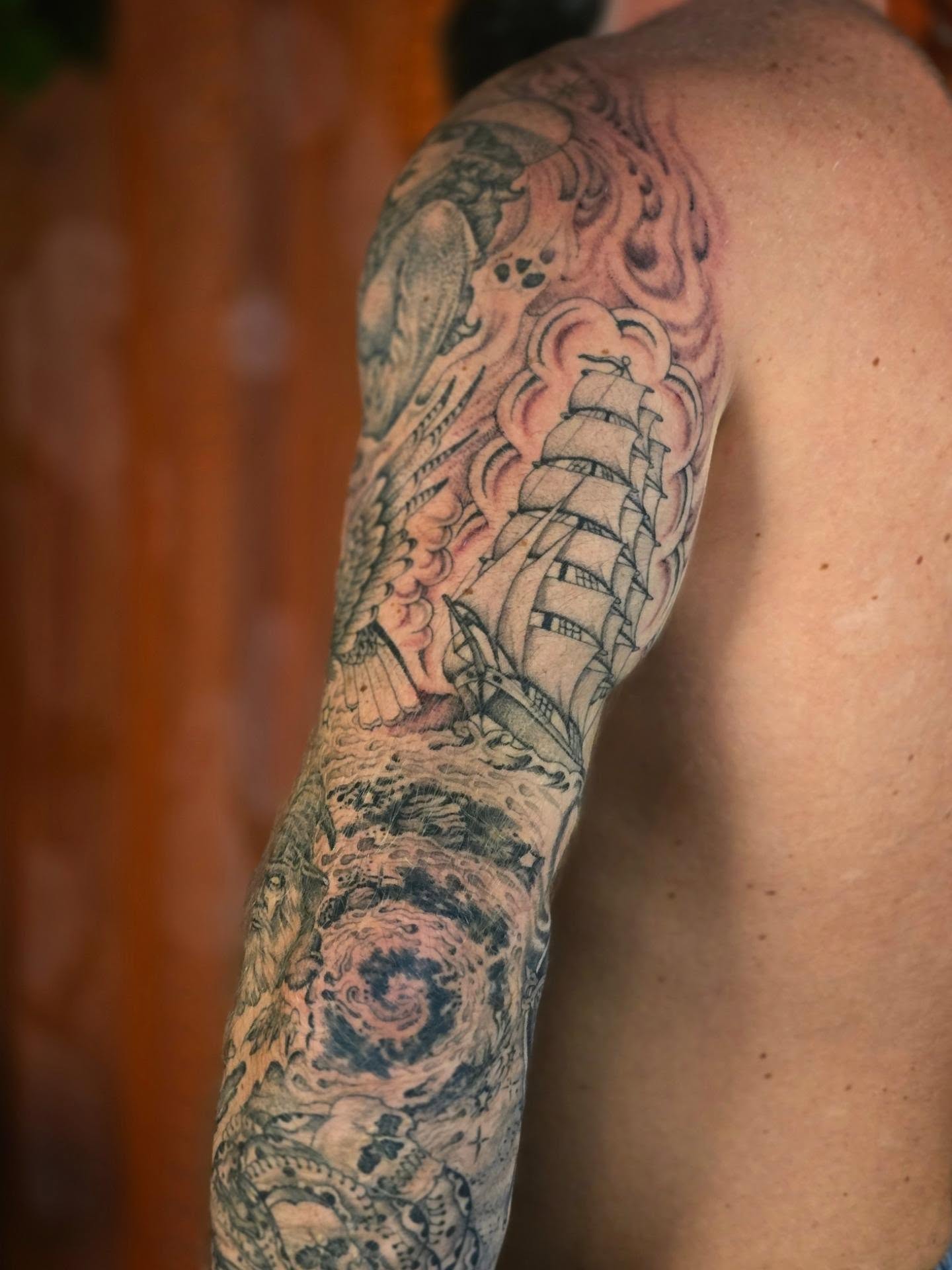 Ship sailing through storm realism tattoo on the upper arm by Aaron Dor