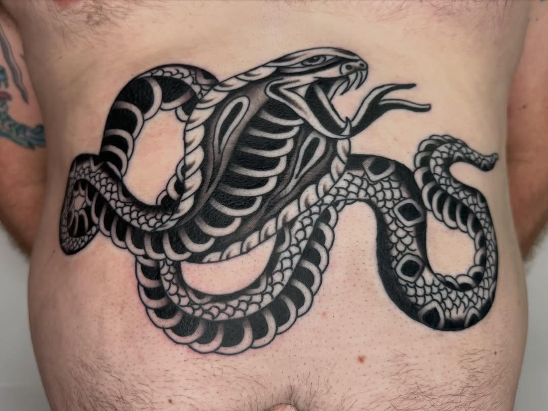 Snake black and grey tattoo on the chest by Jacqui Rose