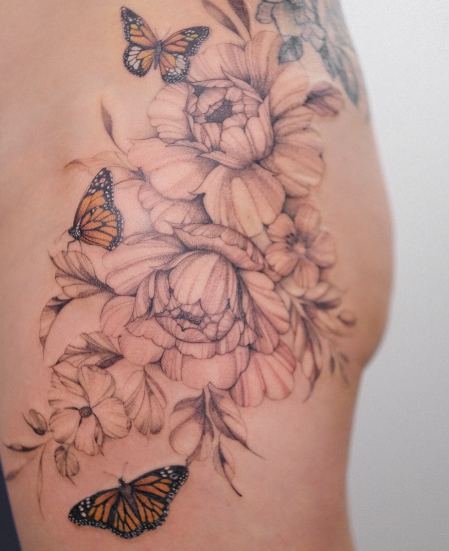 Monarch butterflies and flowers realism tattoo on the thigh by Temple Adorned Tattoo