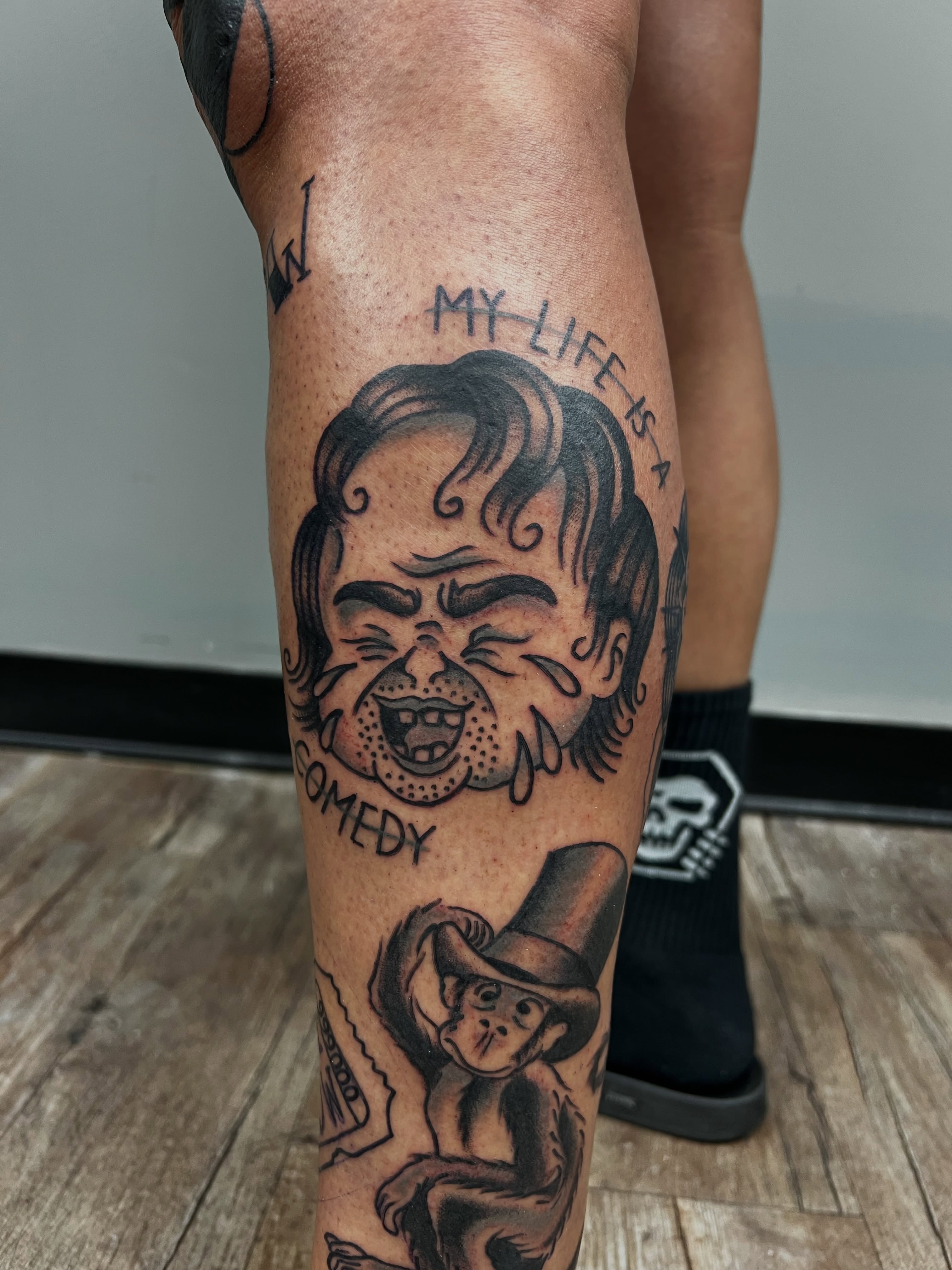 Comedy black and grey tattoo on the forearm by Josh Kronauer