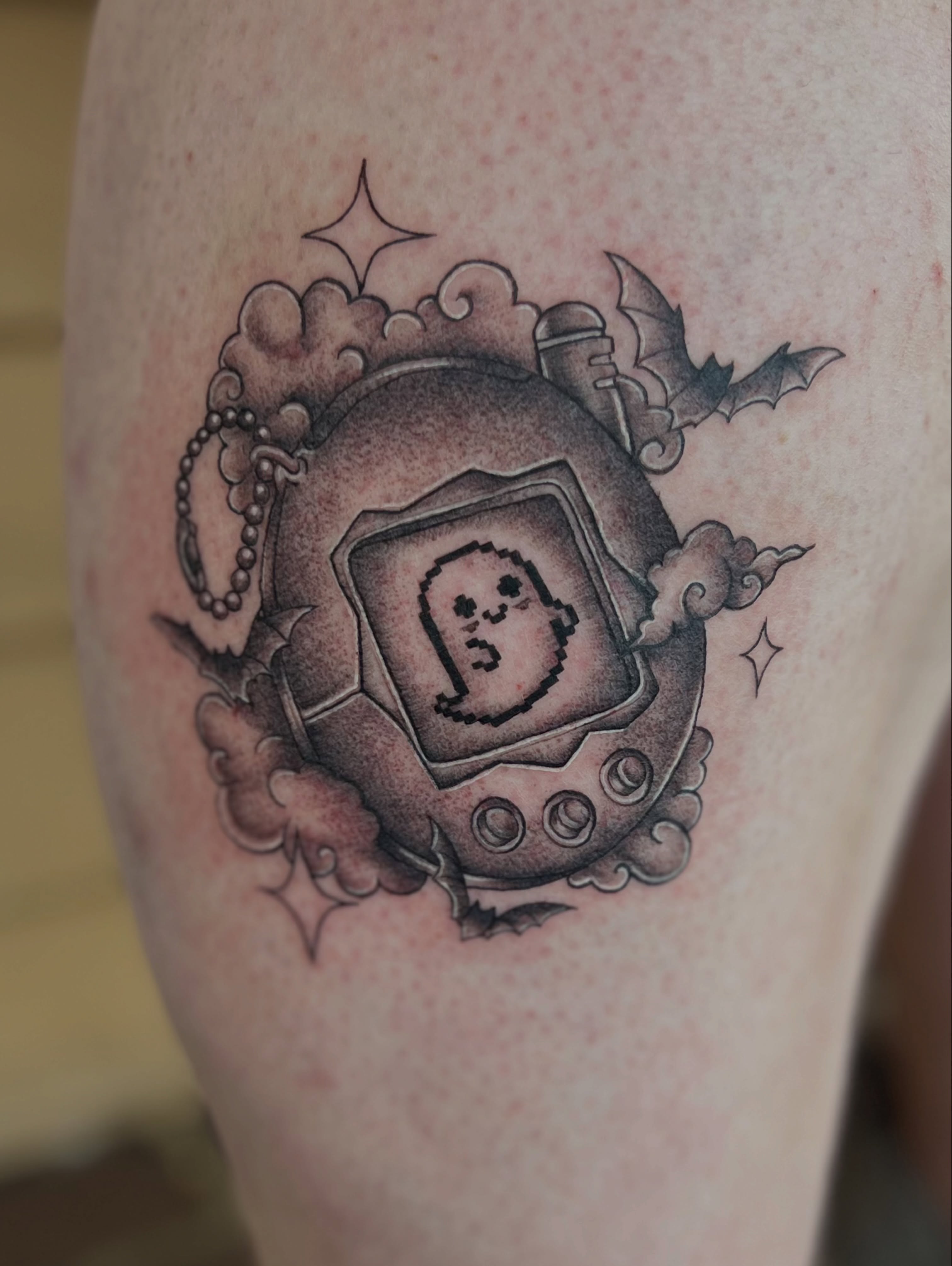 Tamagotchi black and grey tattoo on the forearm by Jai Woods