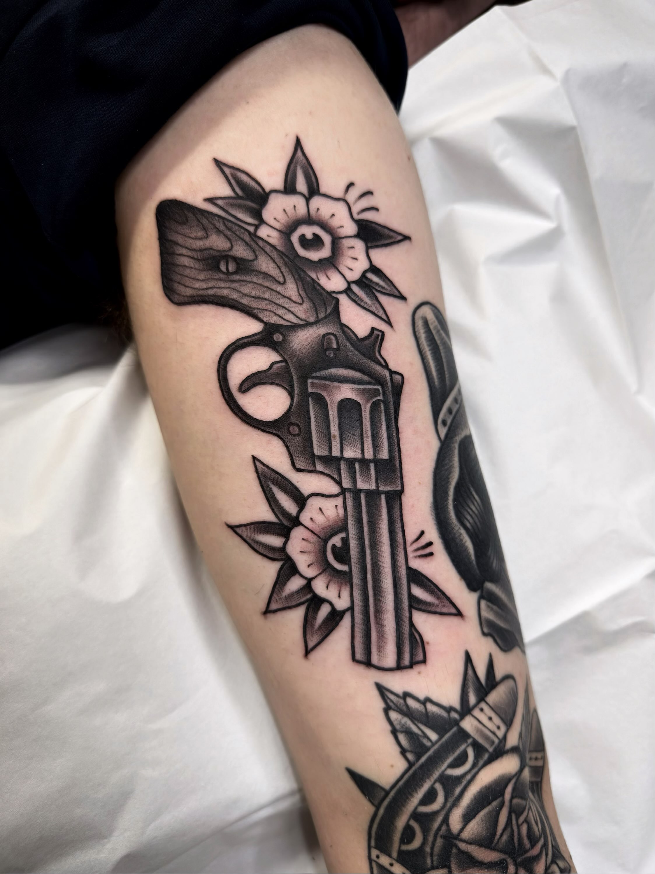 Gun and flower American traditional tattoo on the forearm by Trav, Bayville, New Jersey