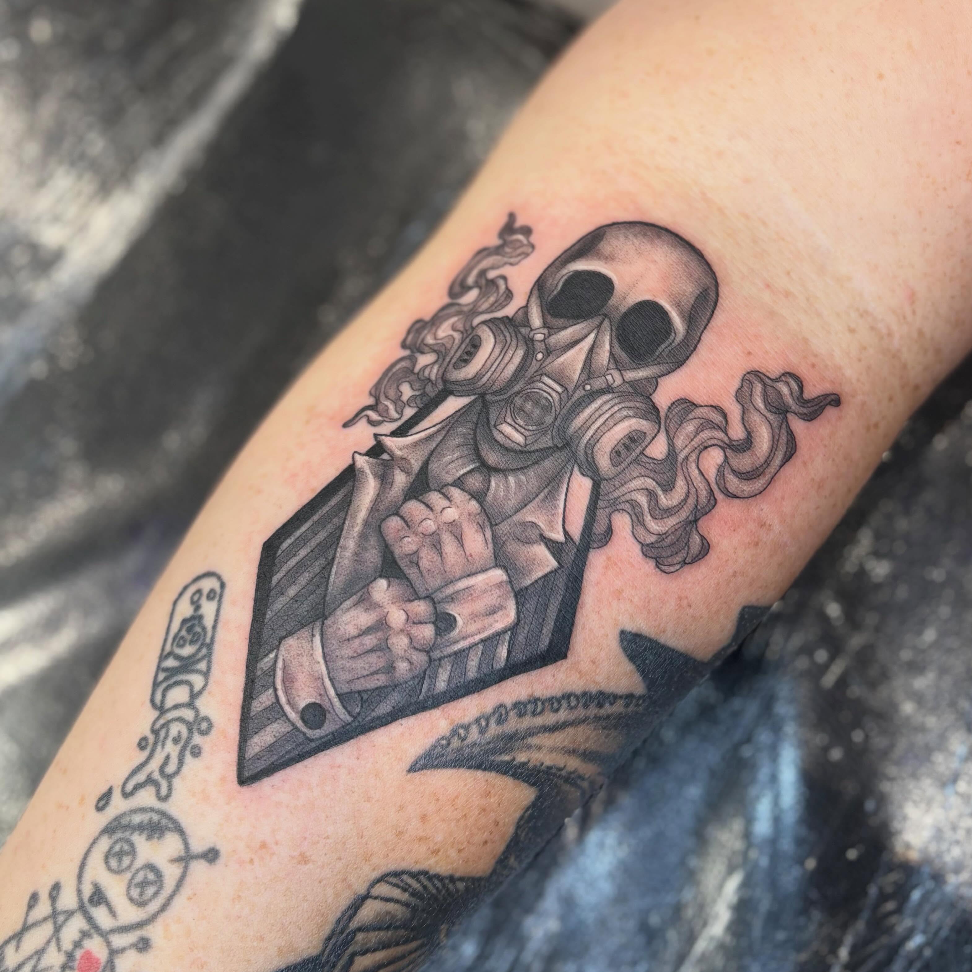Skull wearing gas mask black and grey tattoo on the forearm by Olivia Buch