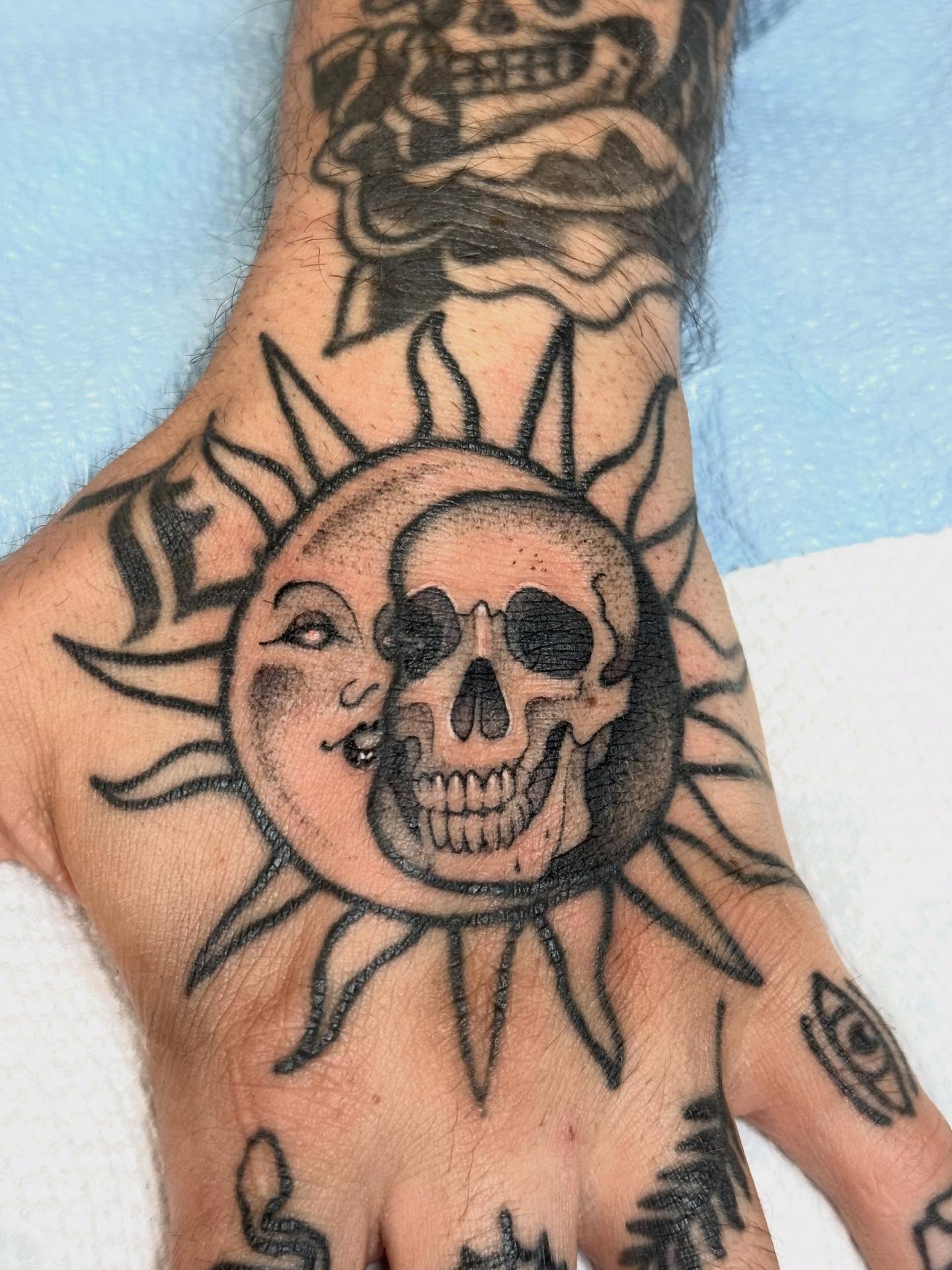 Skull and sun black and grey tattoo on the hand by Mads Ink