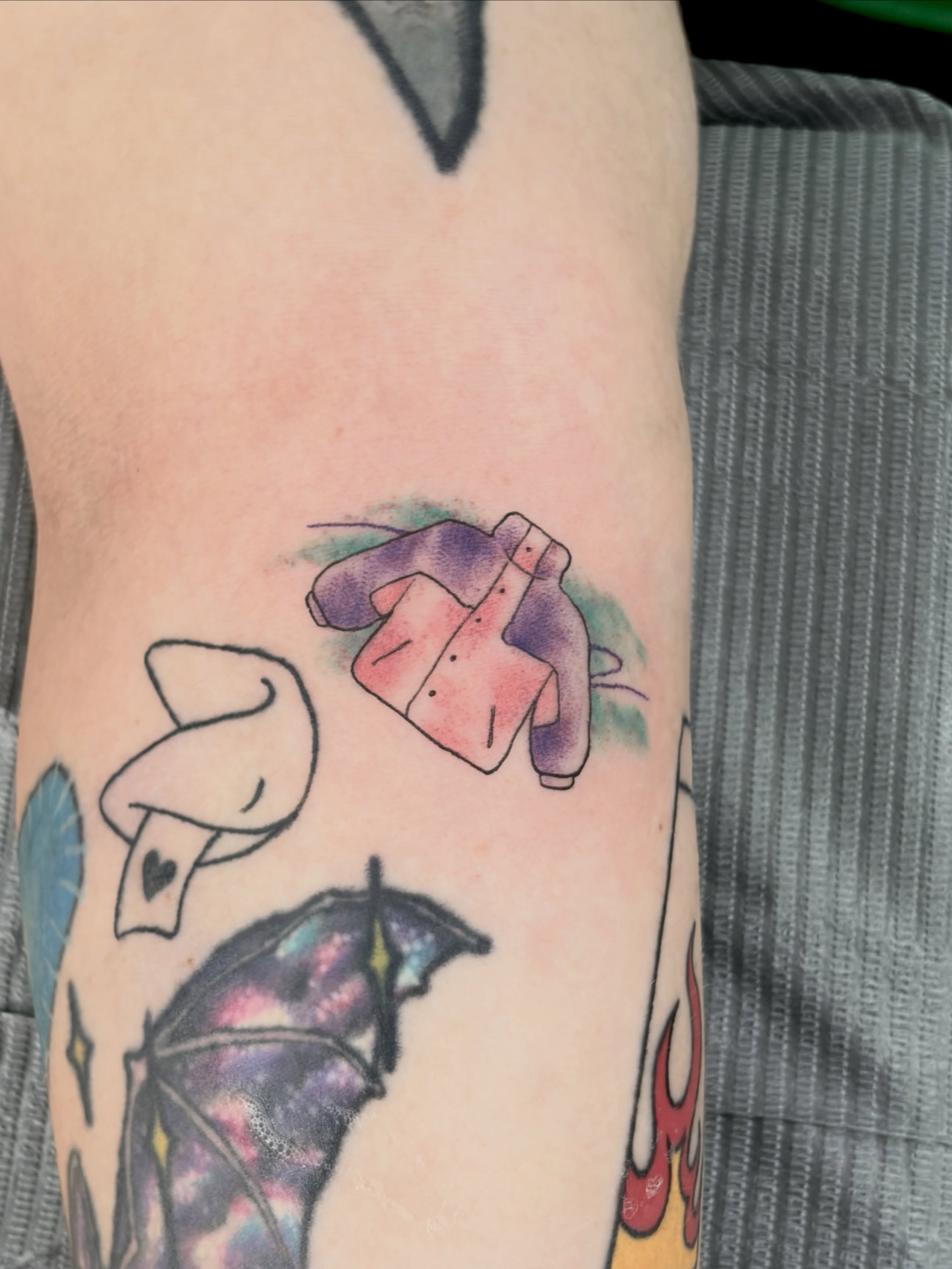 Jacket and umbrella watercolor tattoo on the forearm by Chris, Cleveland, Ohio
