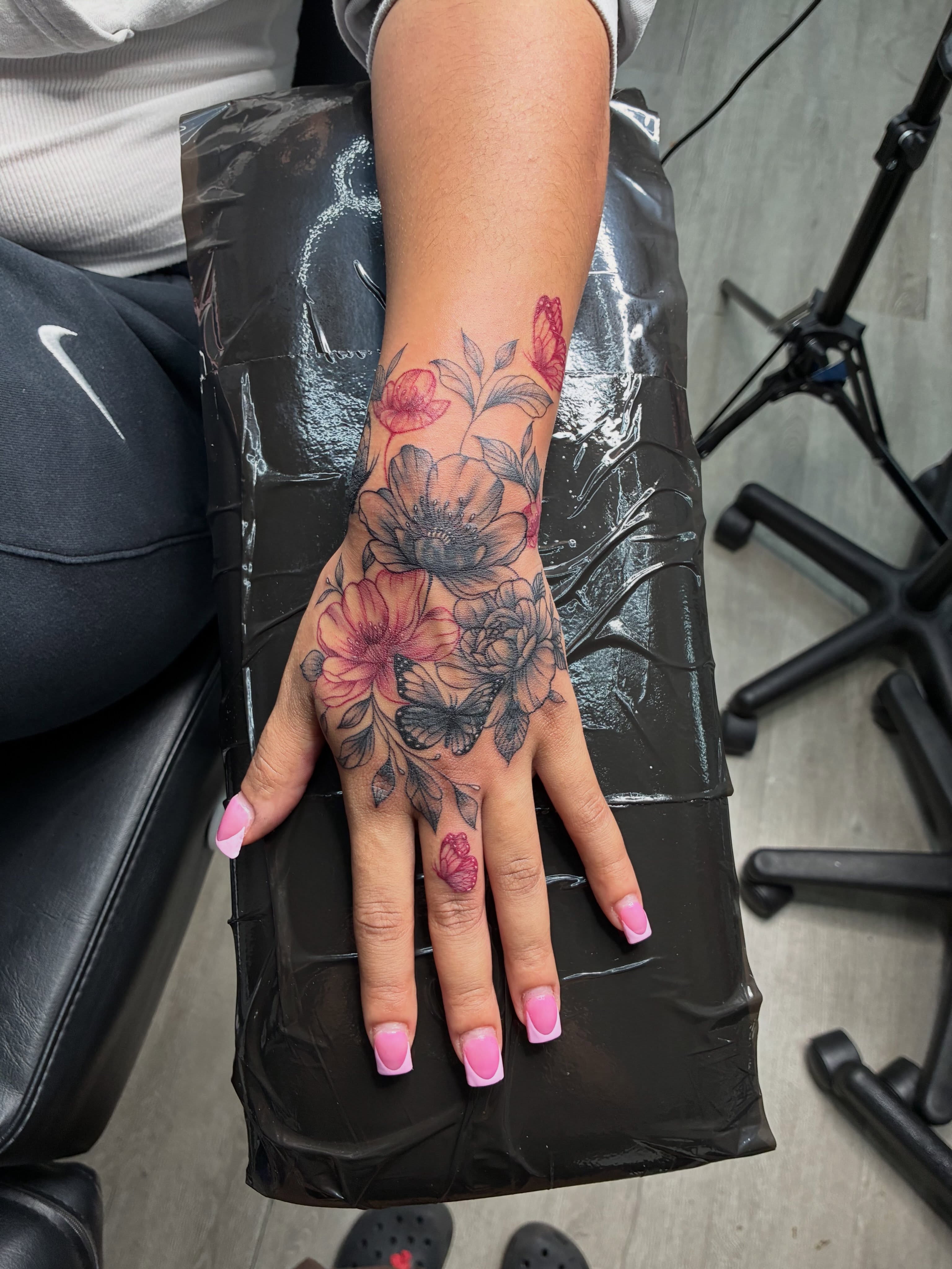 Floral arrangement black and grey tattoo on the hand by Tattoos by Hailey