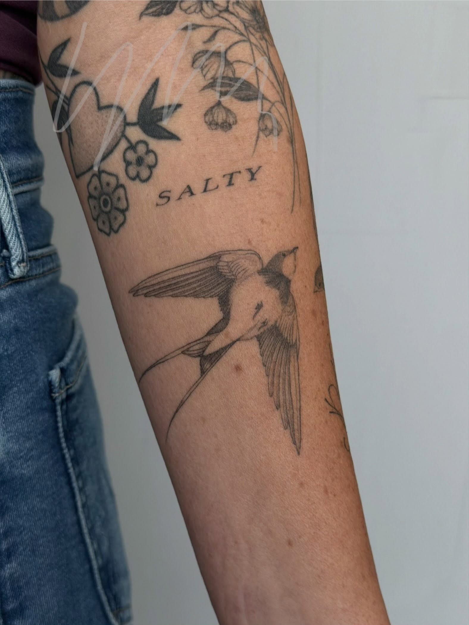 Bird and floral black and grey tattoo on the forearm by Hannah Matthews