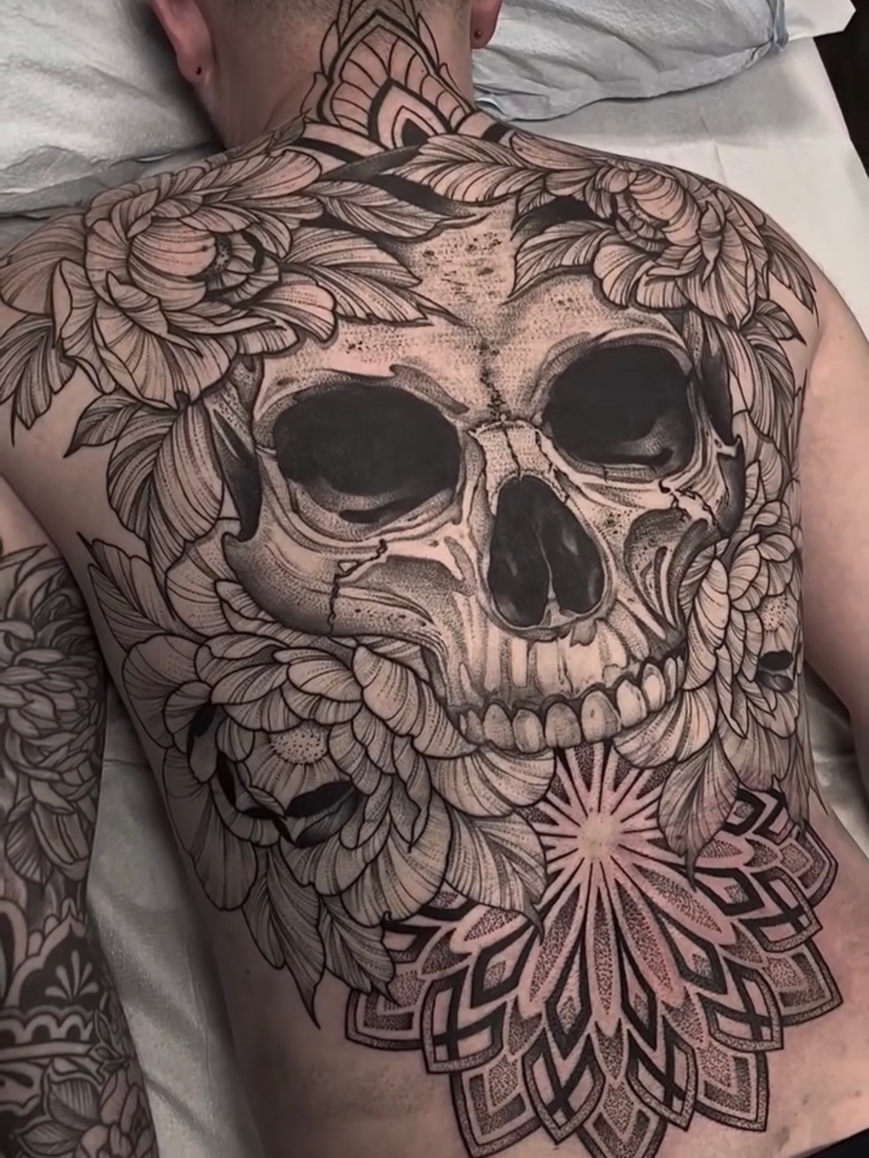 Skull and floral geometric tattoo on the back by Sterling Grice