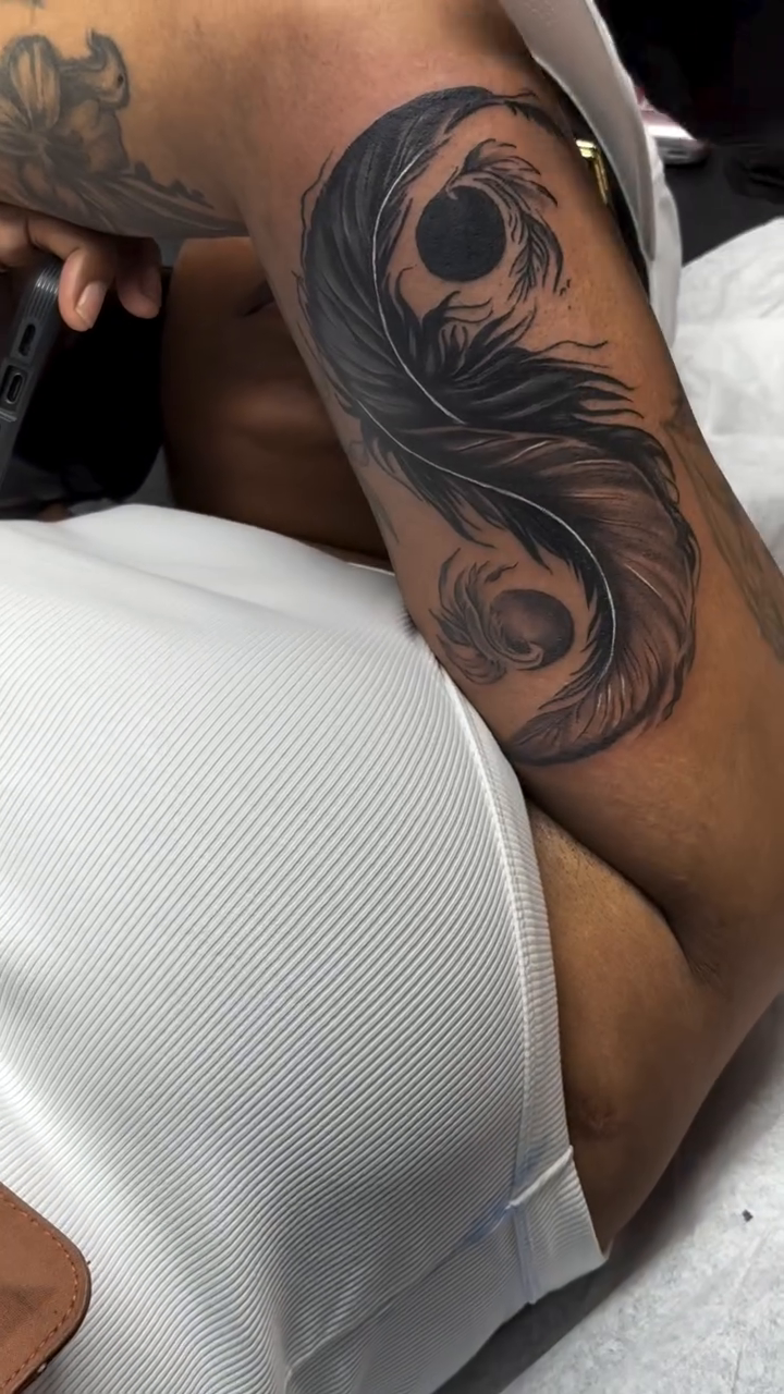 Yin yang symbol with feathers realism tattoo on the upper arm by Jose Onasis Disla, New York, New York