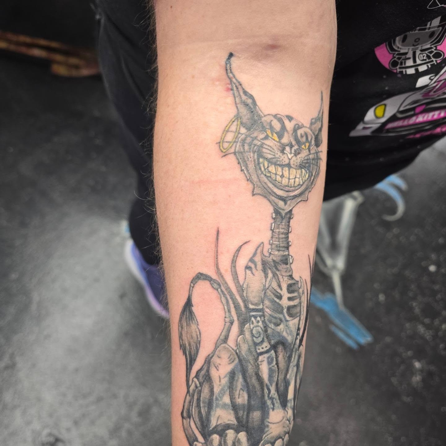 Cheshire cat black and grey tattoo on the forearm by Maddox Kitson🕷