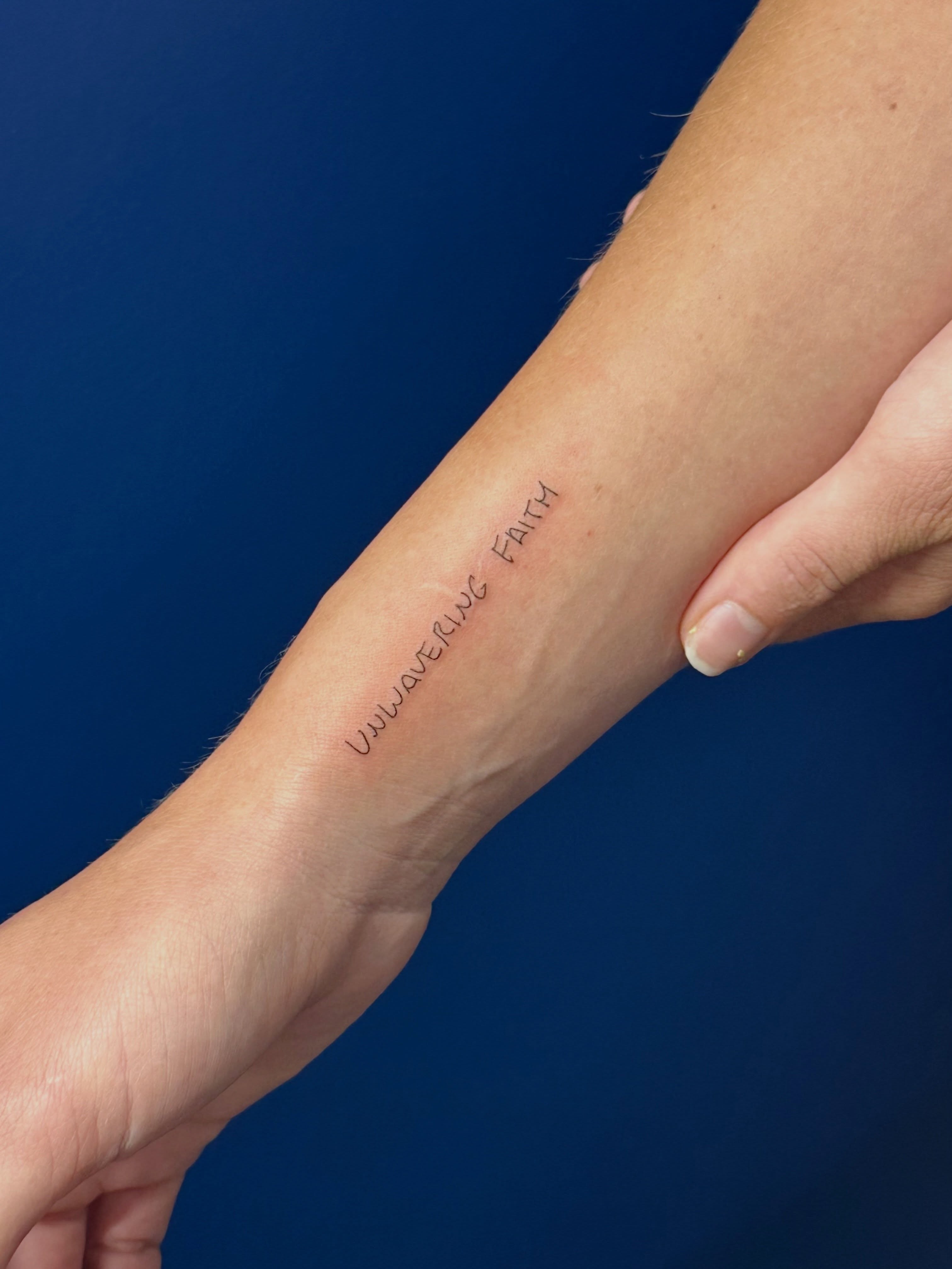 Unwavering faith lettering script tattoo on the forearm by Tattoo Takayo