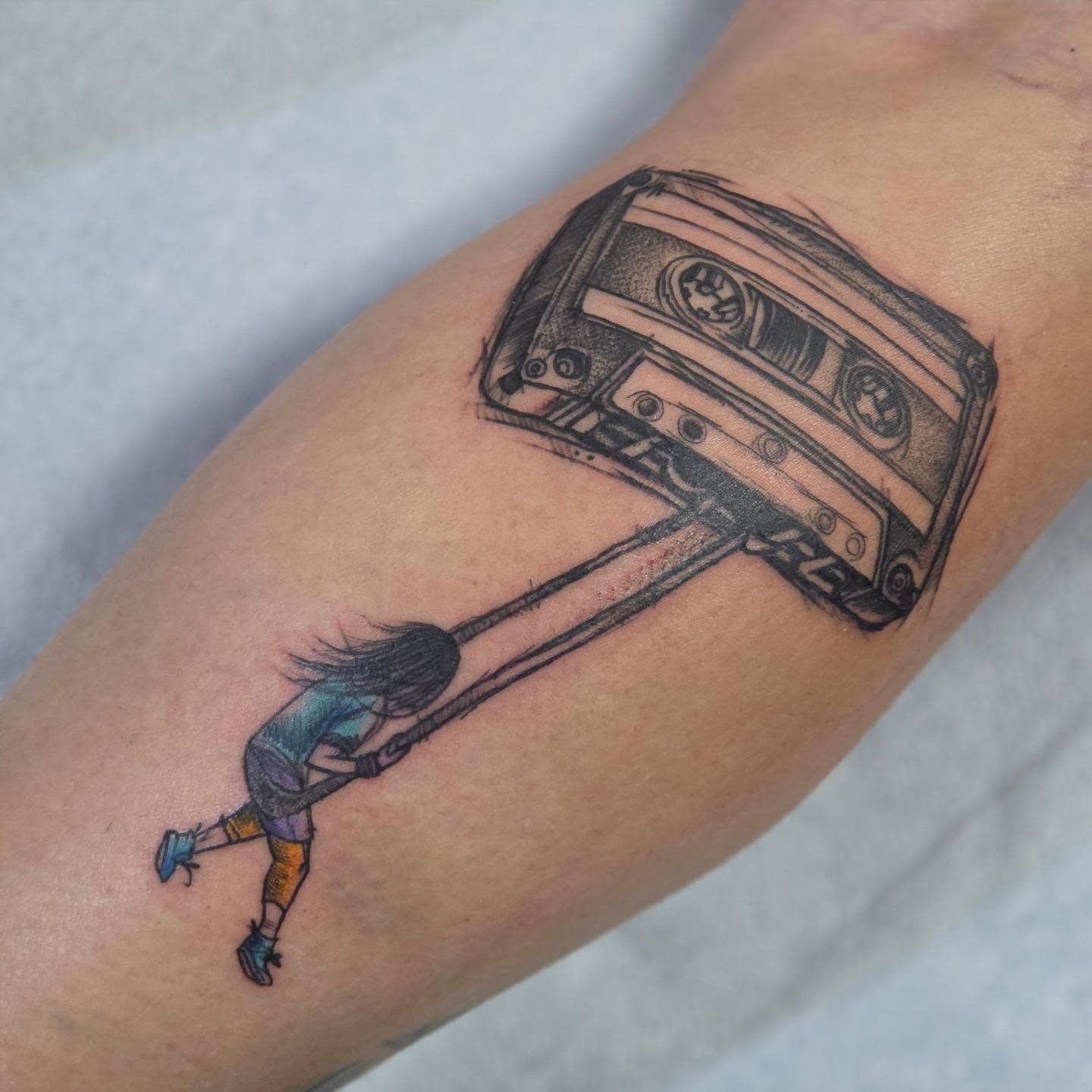 Cassette tape pulling girl realism tattoo on the forearm by Robert Glover