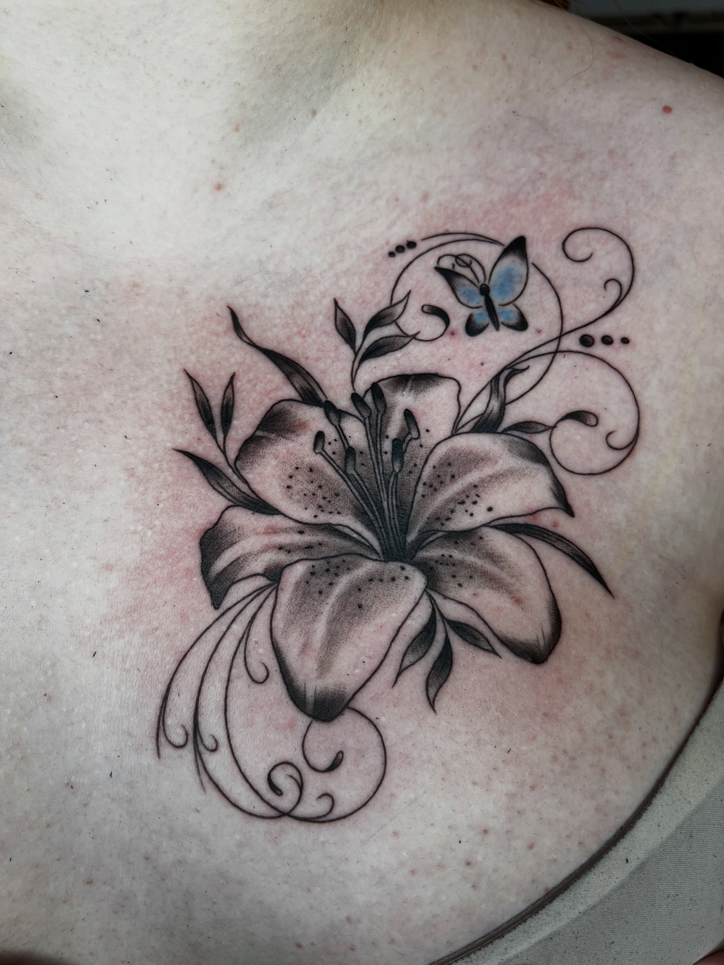 Lily and butterfly black and grey tattoo on the chest by Cory Miller