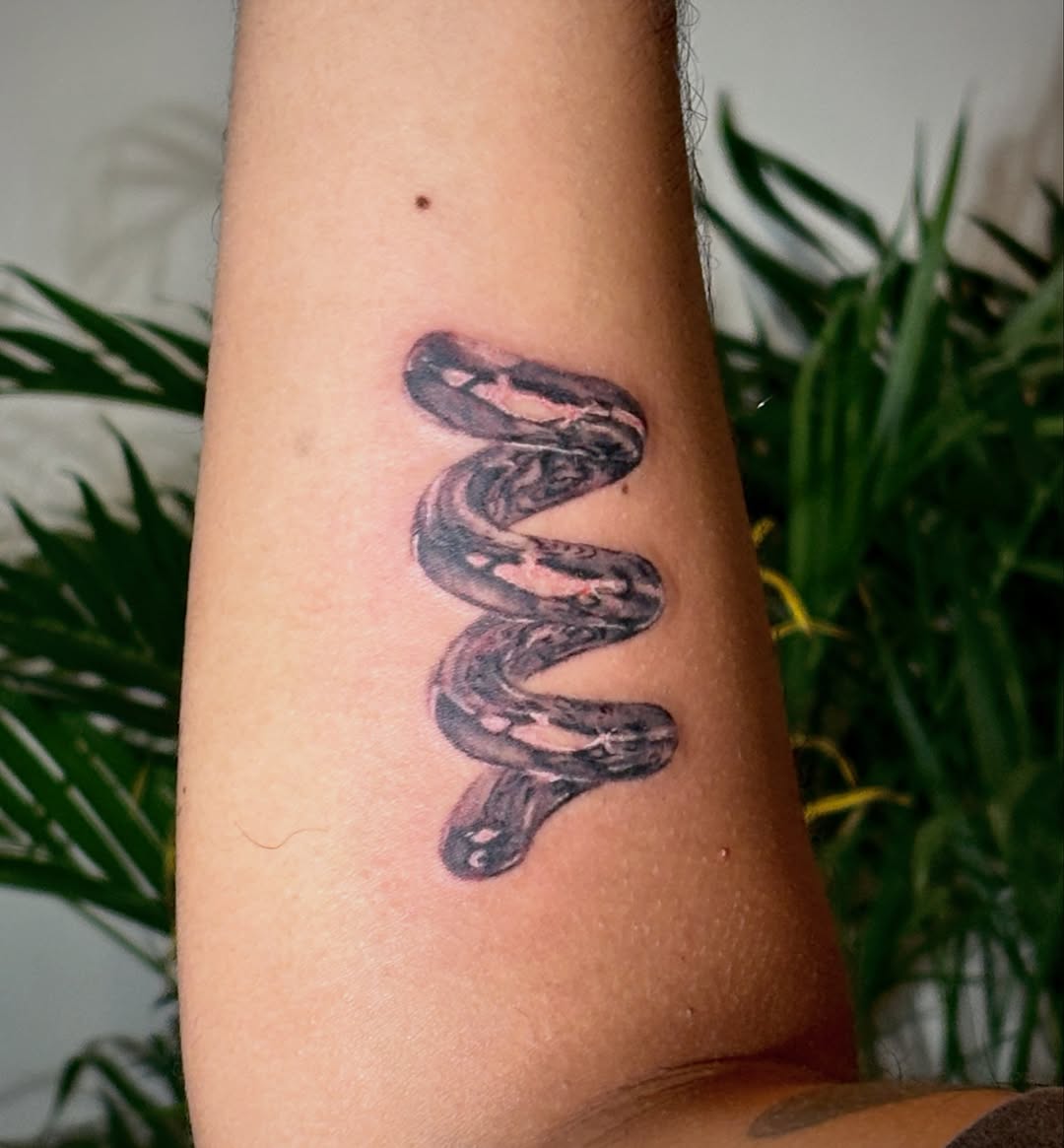 Coiled snake surrealism tattoo on the forearm by *:・kelly✧*:・゚