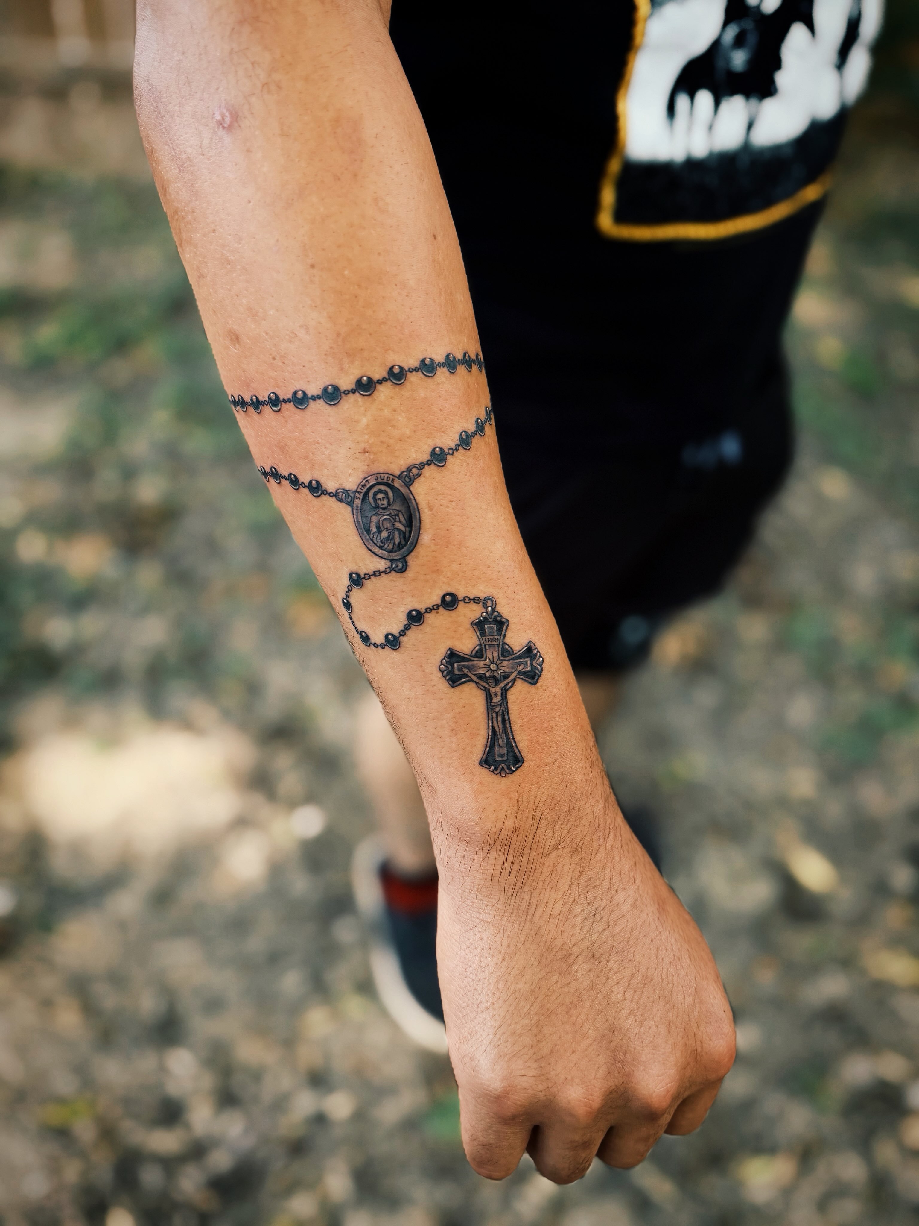 Rosary and cross black and grey tattoo on the forearm by @amandahowtattoo