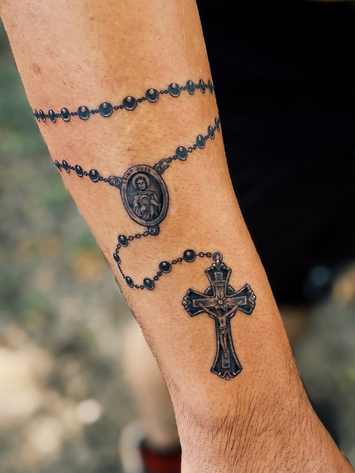 Rosary and cross black and grey tattoo on the forearm by @amandahowtattoo