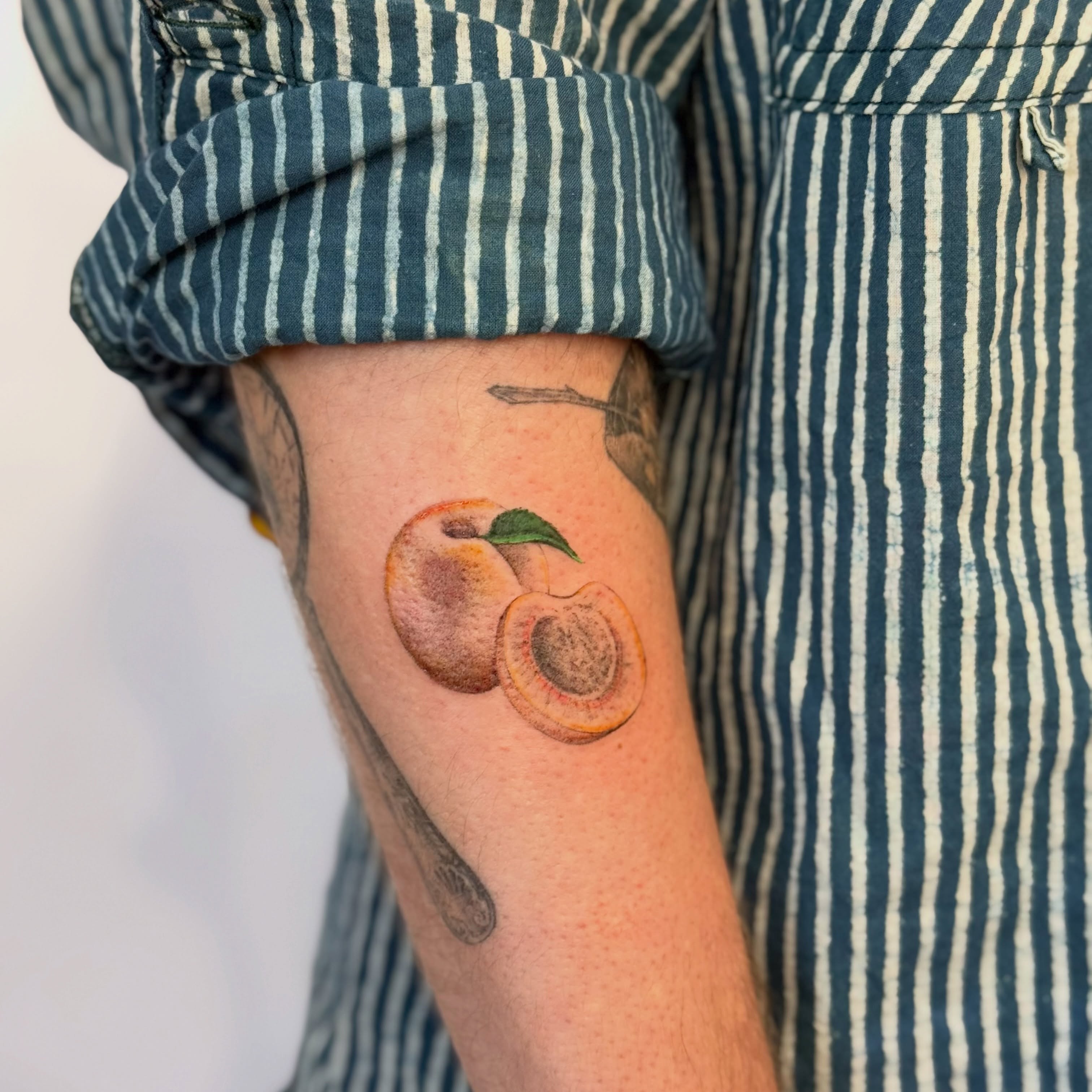 Peach realism tattoo on the forearm by bre