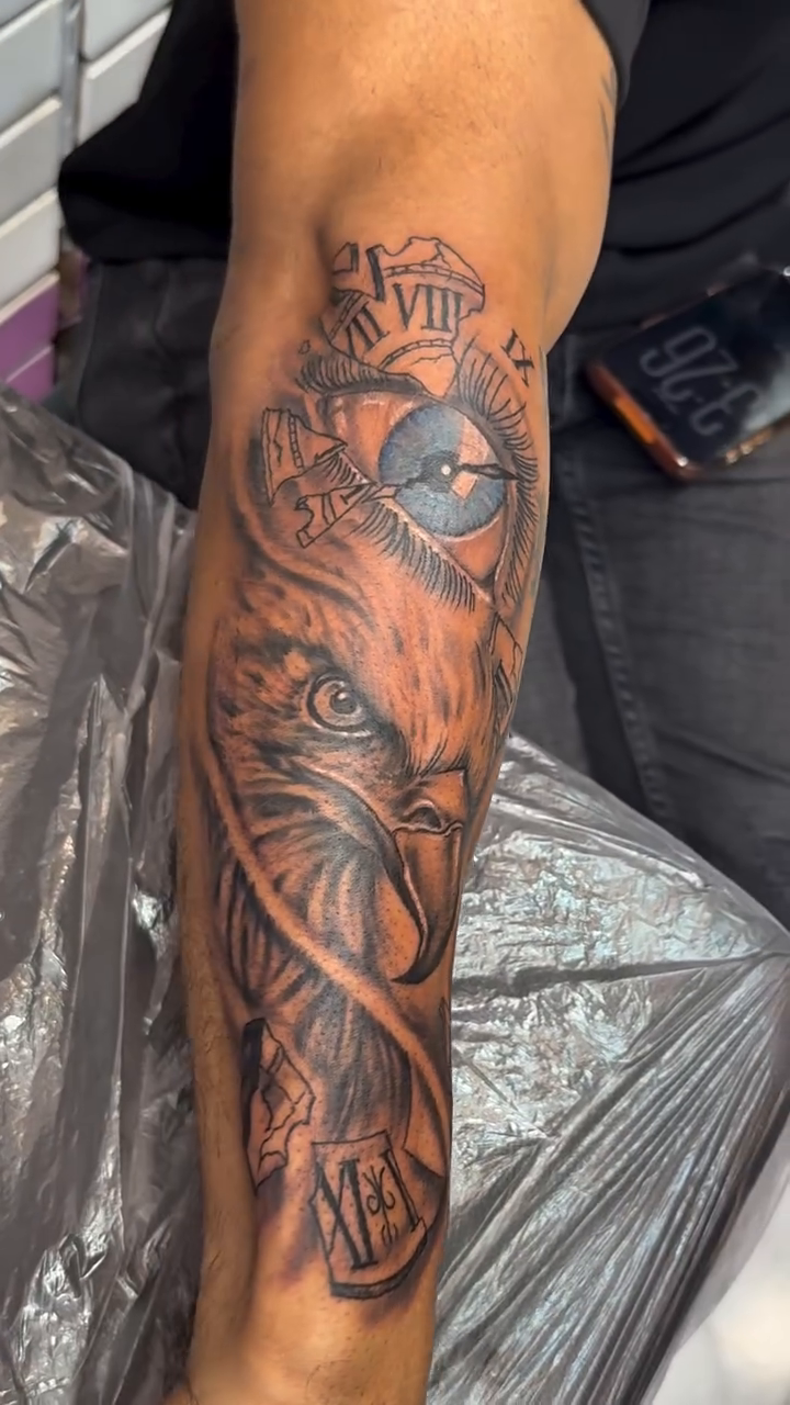 Eagle head and clock face surrealism tattoo on the forearm by Jose Onasis Disla, New York, New York