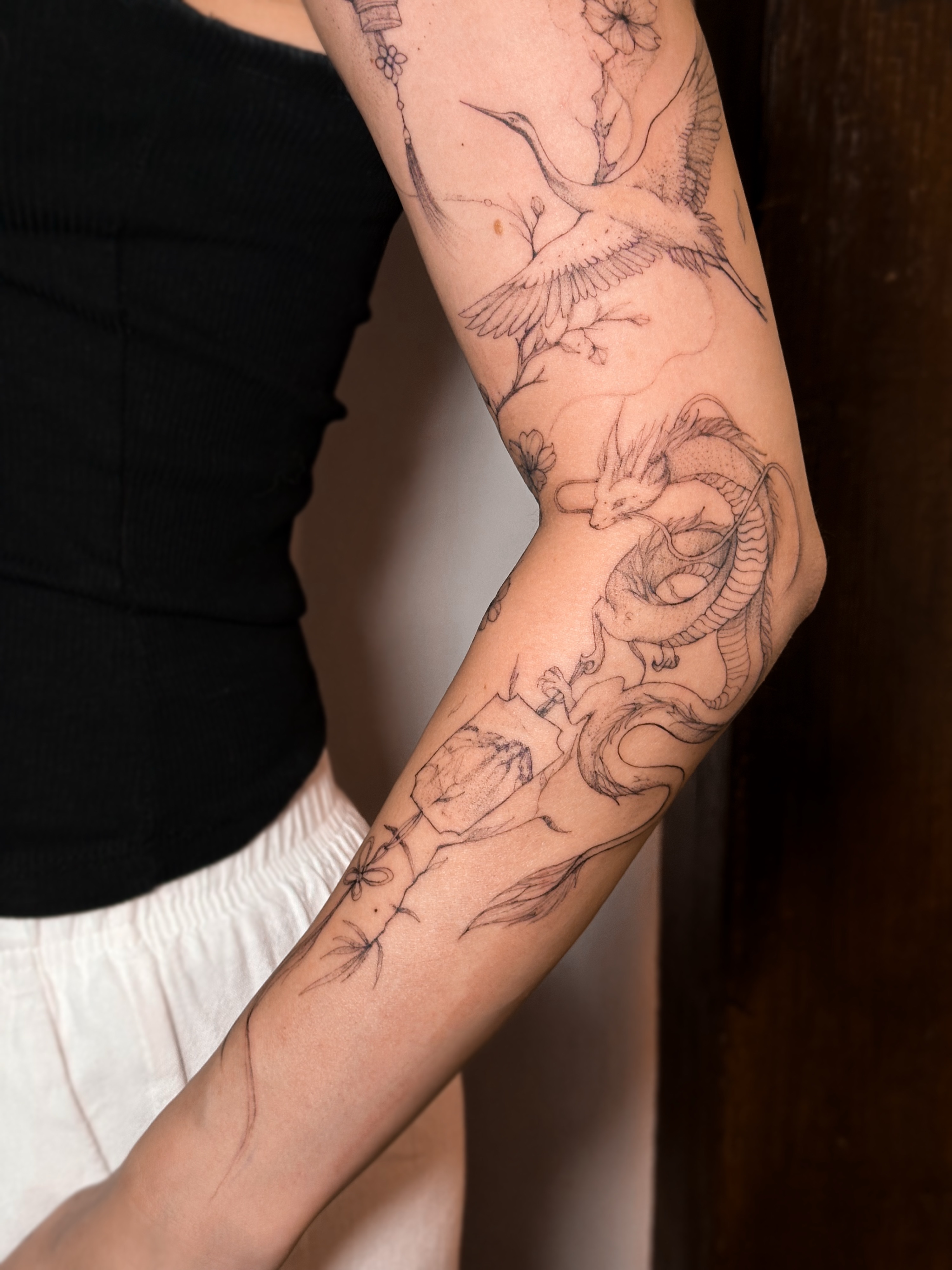 Dragon and crane black and grey tattoo on the forearm by Mila, Riga, Latvia
