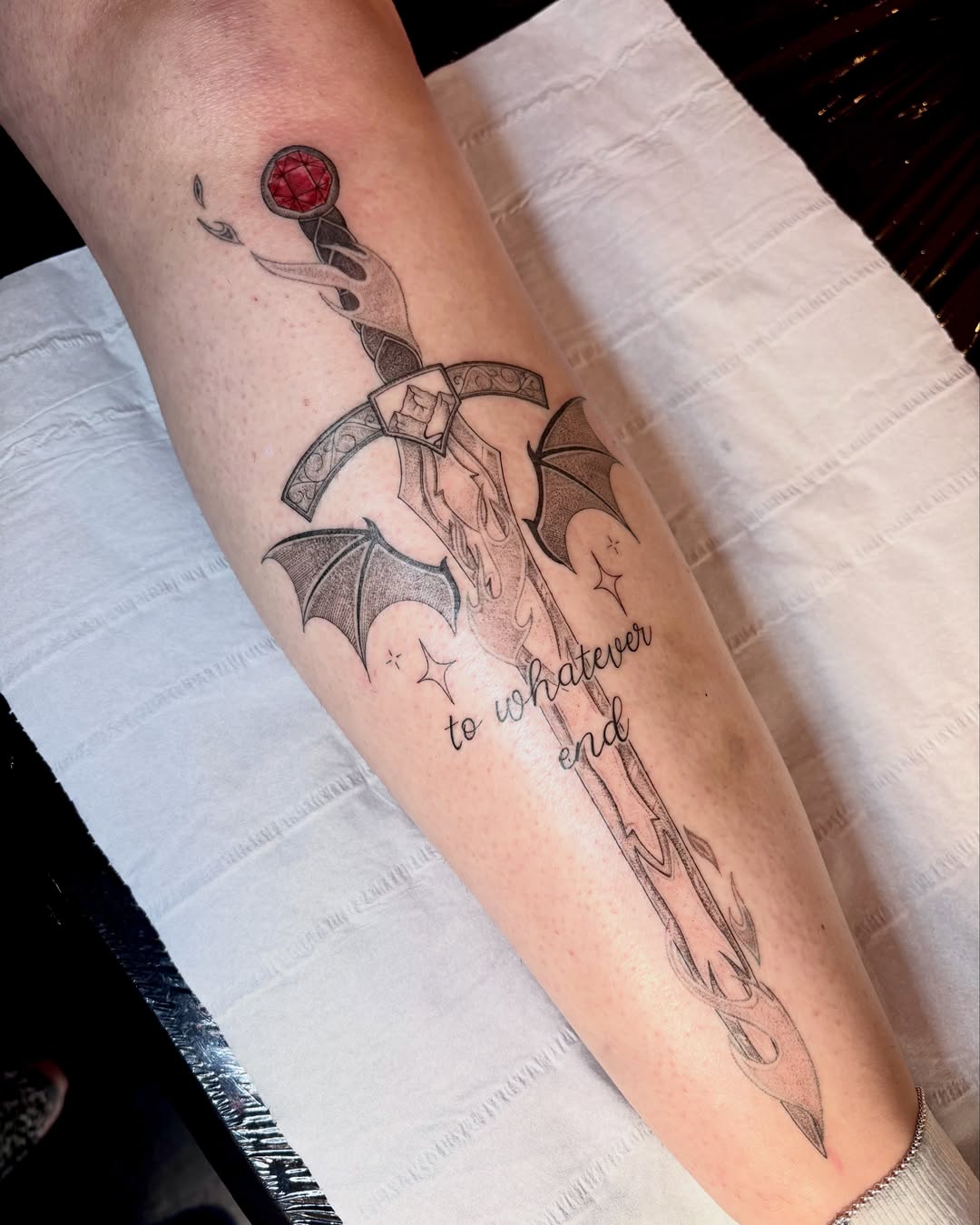 Sword with bat wings black and grey tattoo on the forearm by Charlotte Brown, Leeds, England