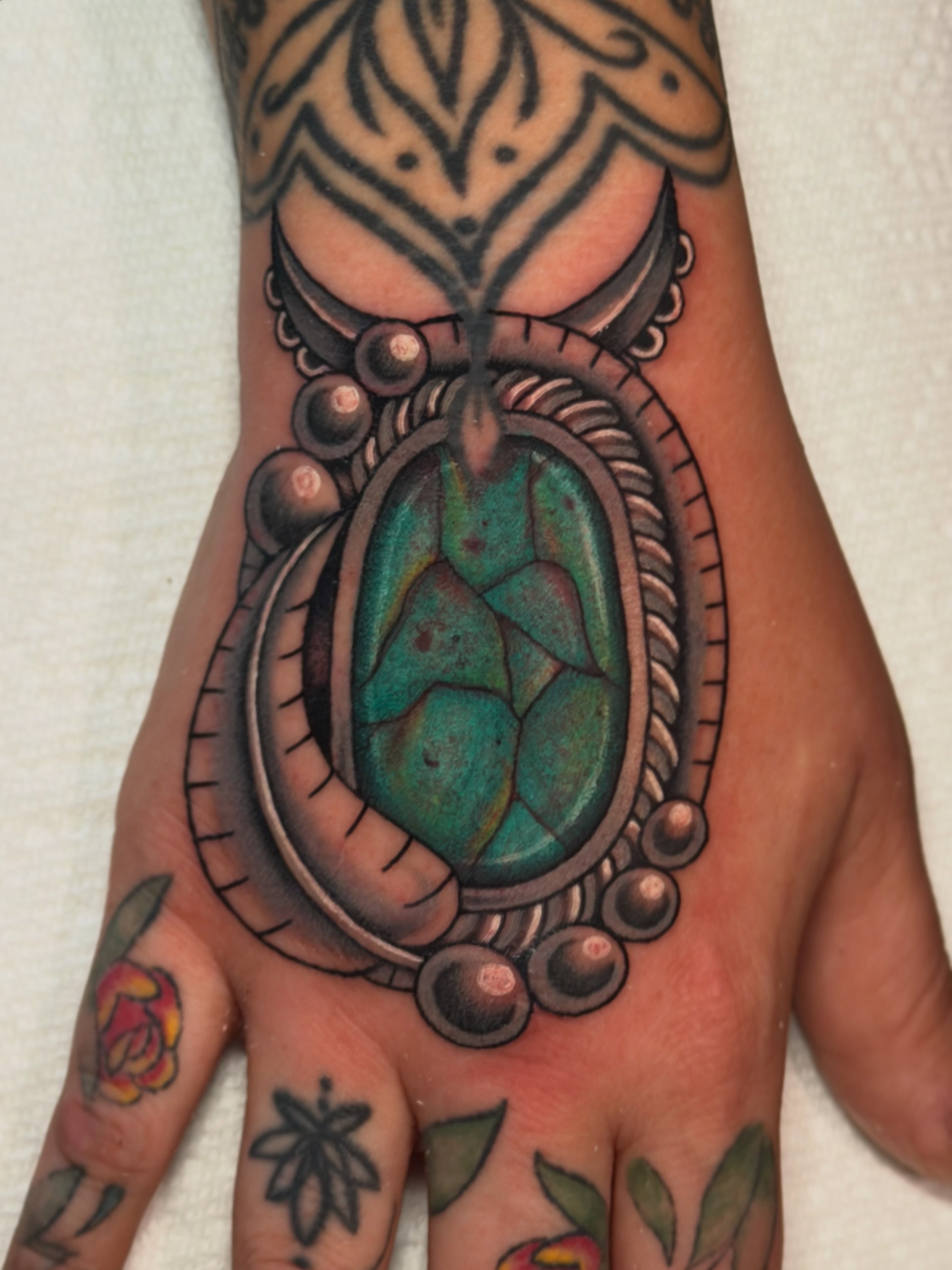 Jeweled pendant American traditional tattoo on the hand by Madison ‘Maddog’ Stewart