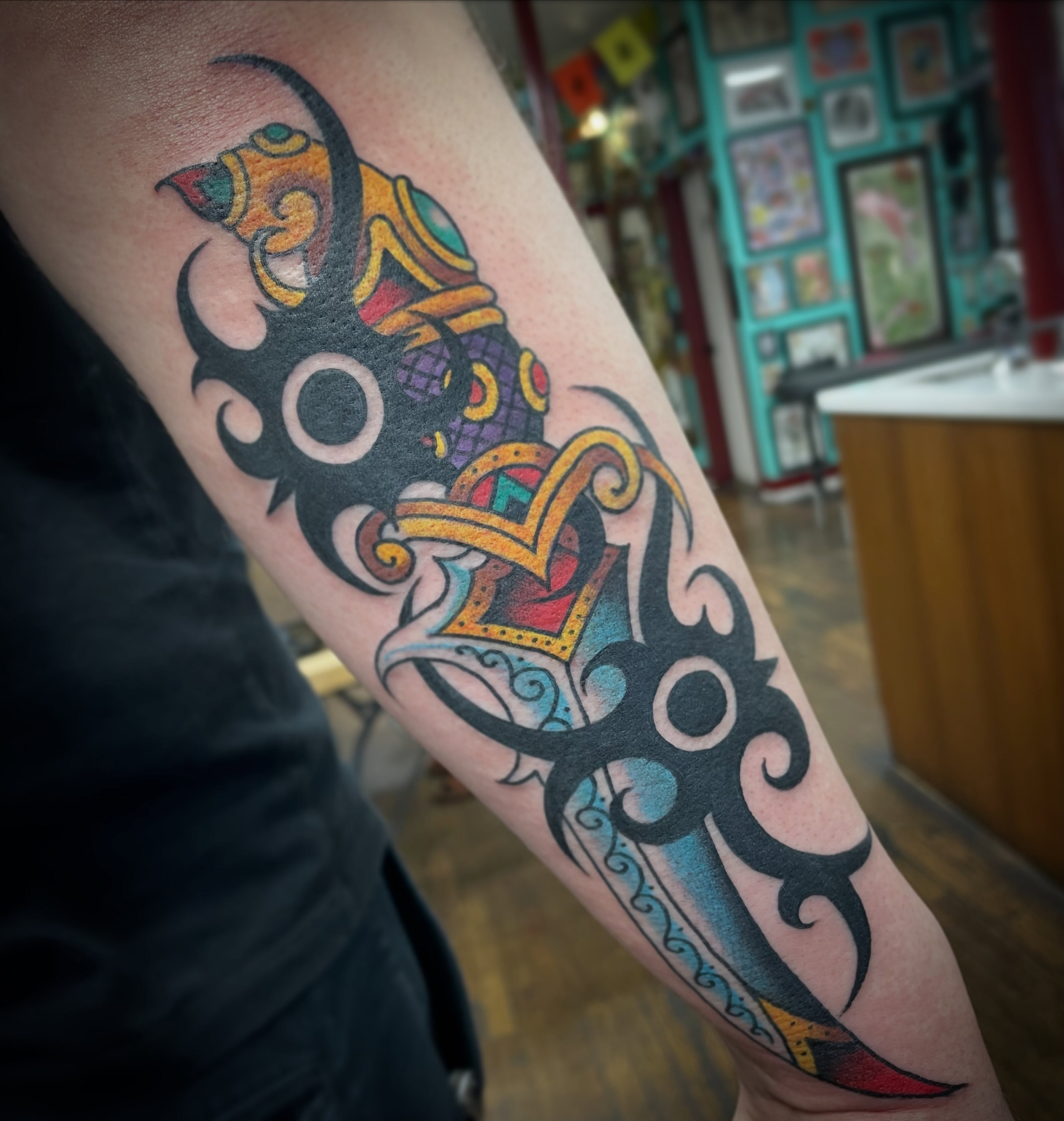 Mask with crown tribal tattoo on the forearm by Haley McMahon