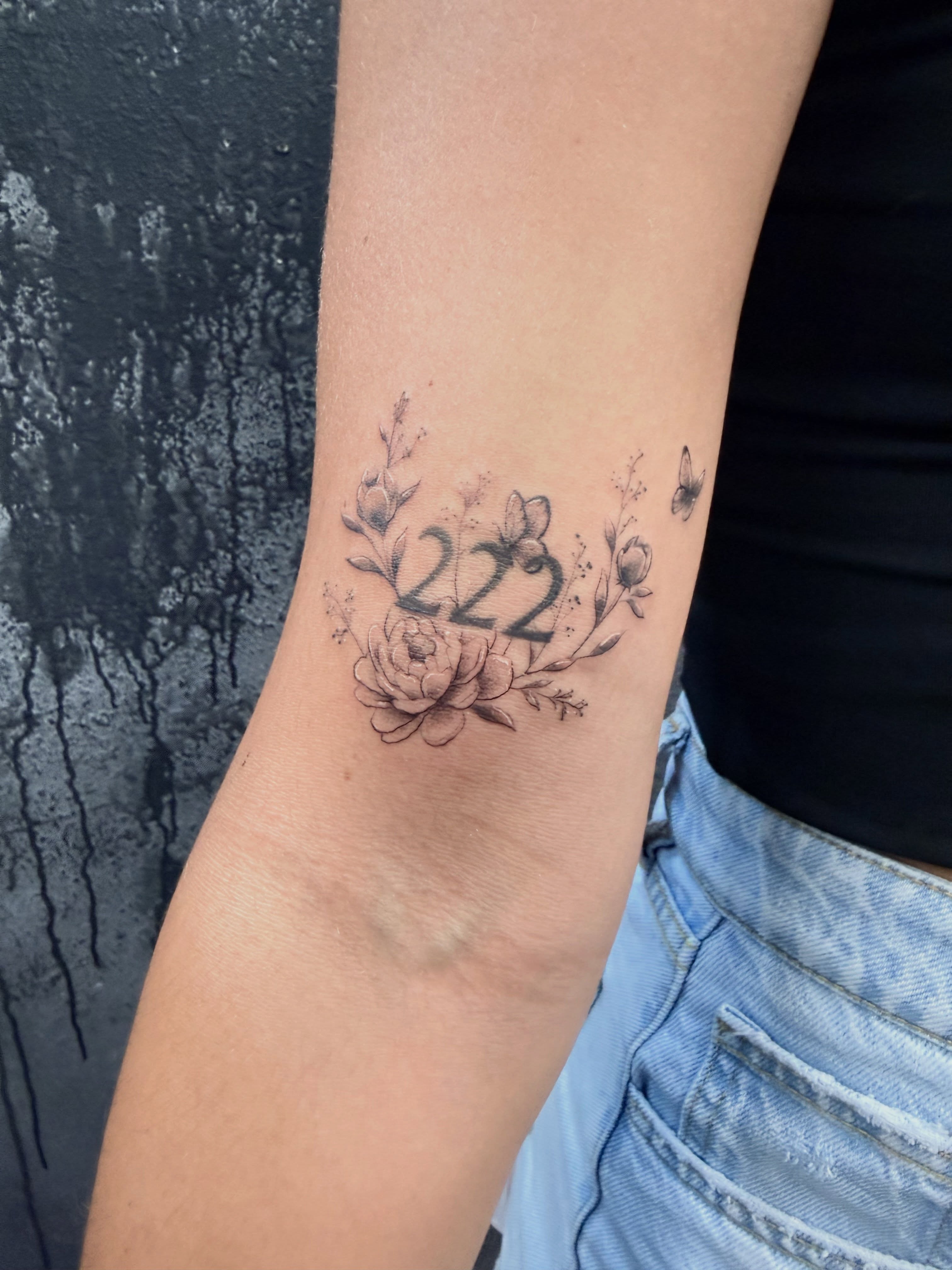 Number 222 with floral elements black and grey tattoo on the forearm by Chris