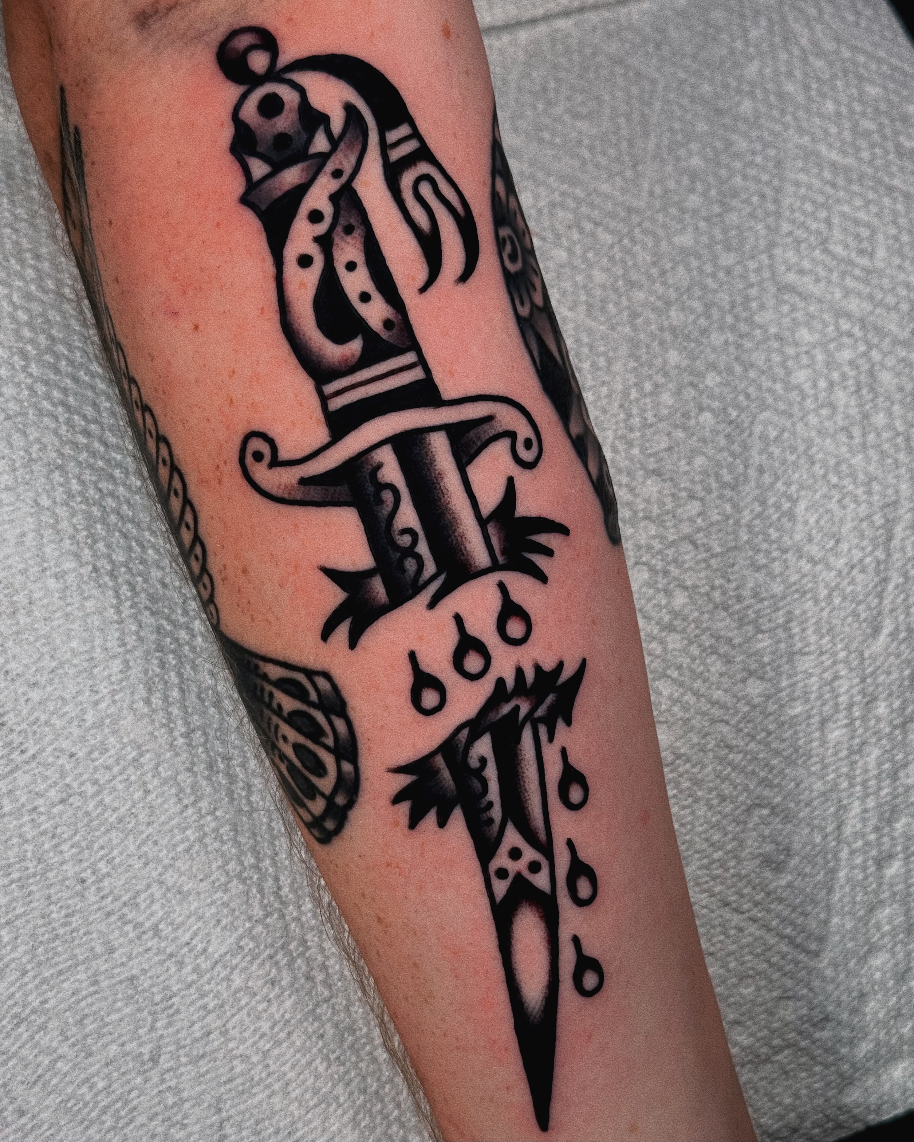 Knife with dripping blood black and grey tattoo on the forearm by Sean Michel, Nashua, New Hampshire