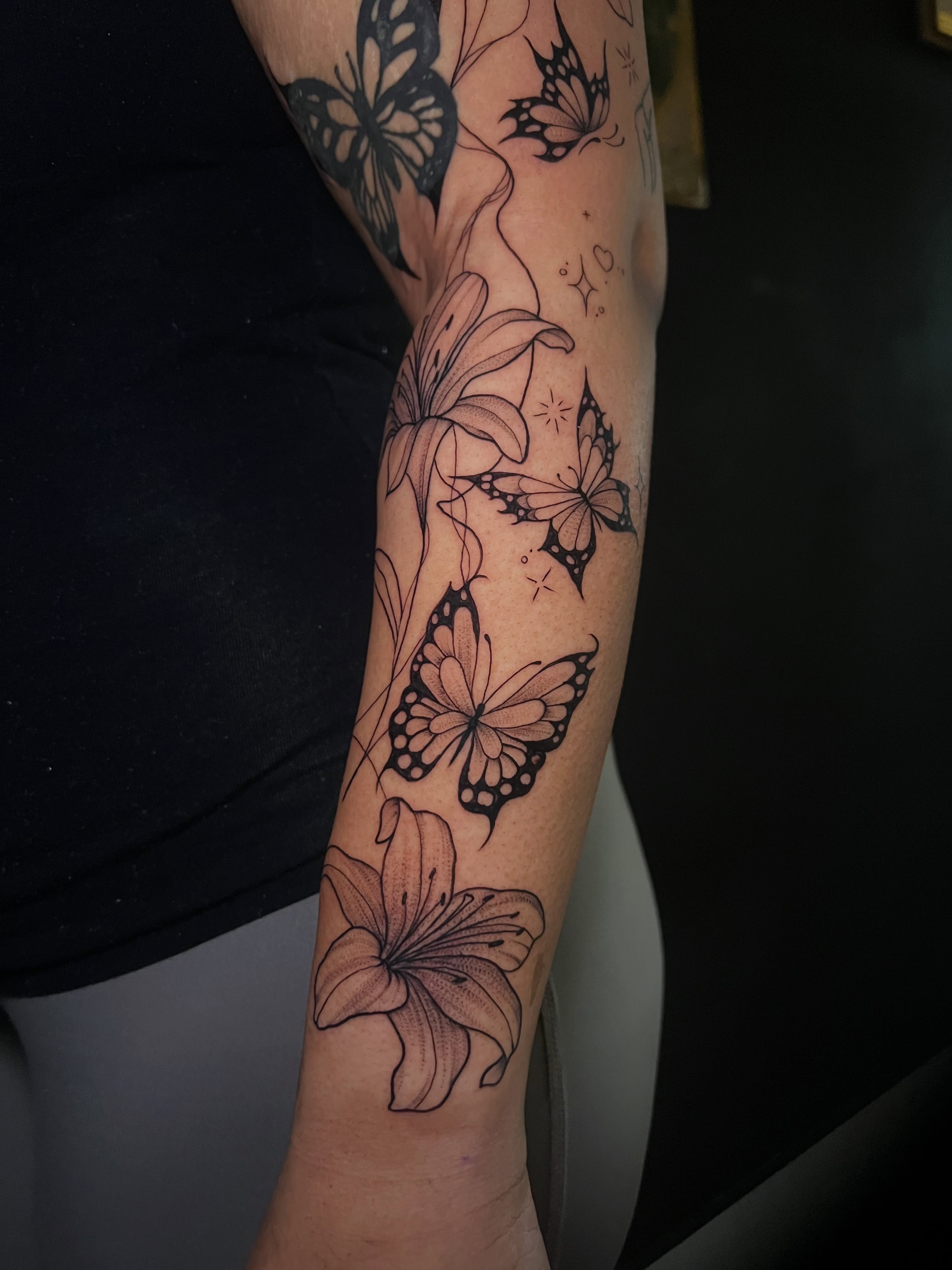 Butterflies and lilies black and grey tattoo on the forearm by Baung Ben