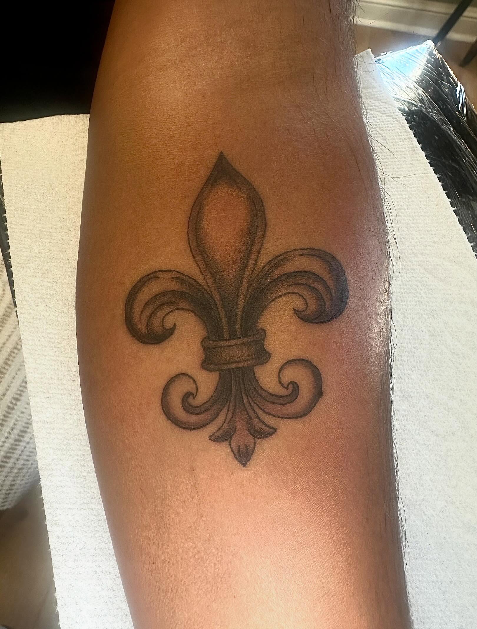 Fleur-de-lis black and grey tattoo on the forearm by Kaylee Woods