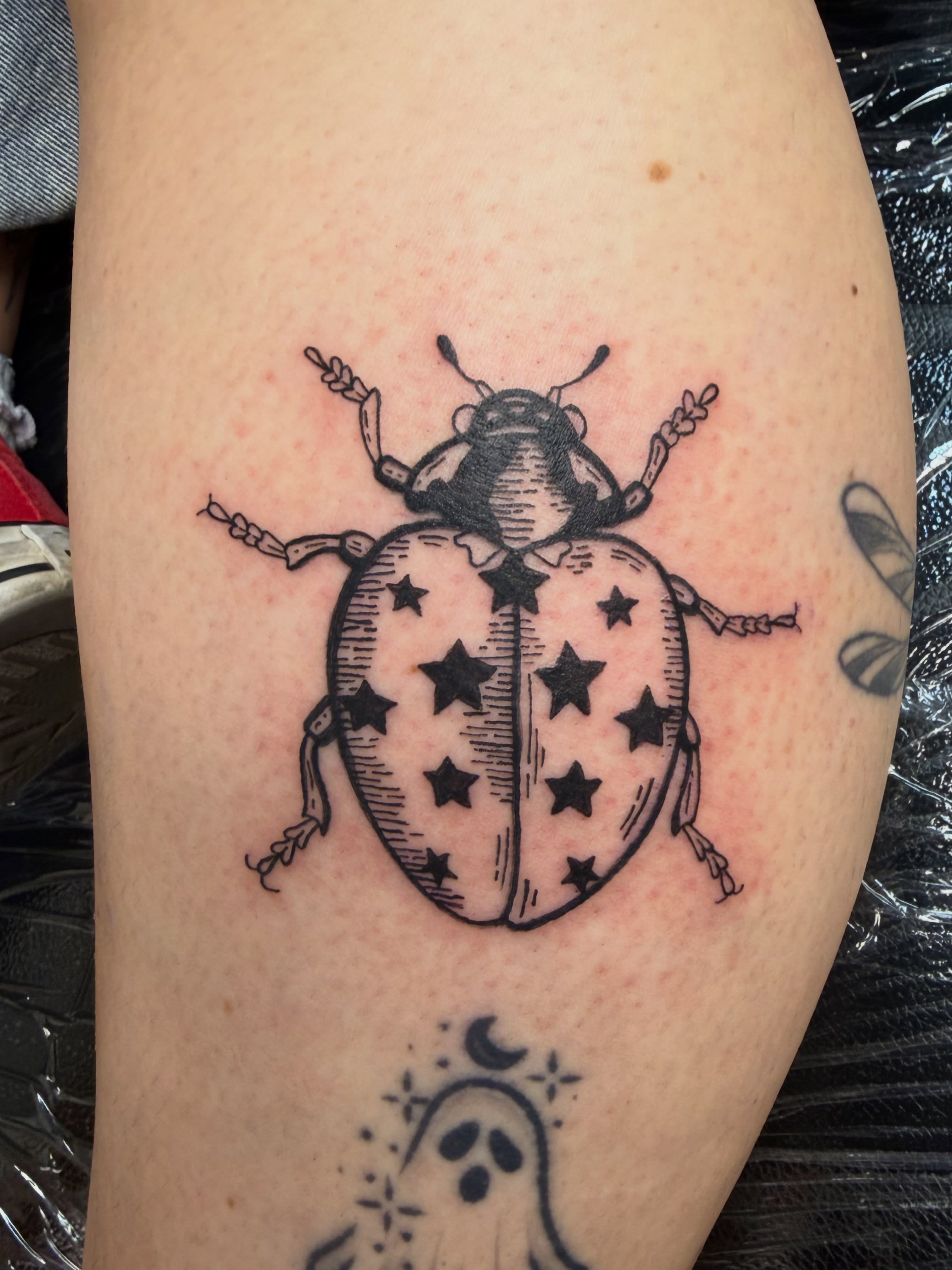 Ladybug black and grey tattoo on the thigh by Laura🦋